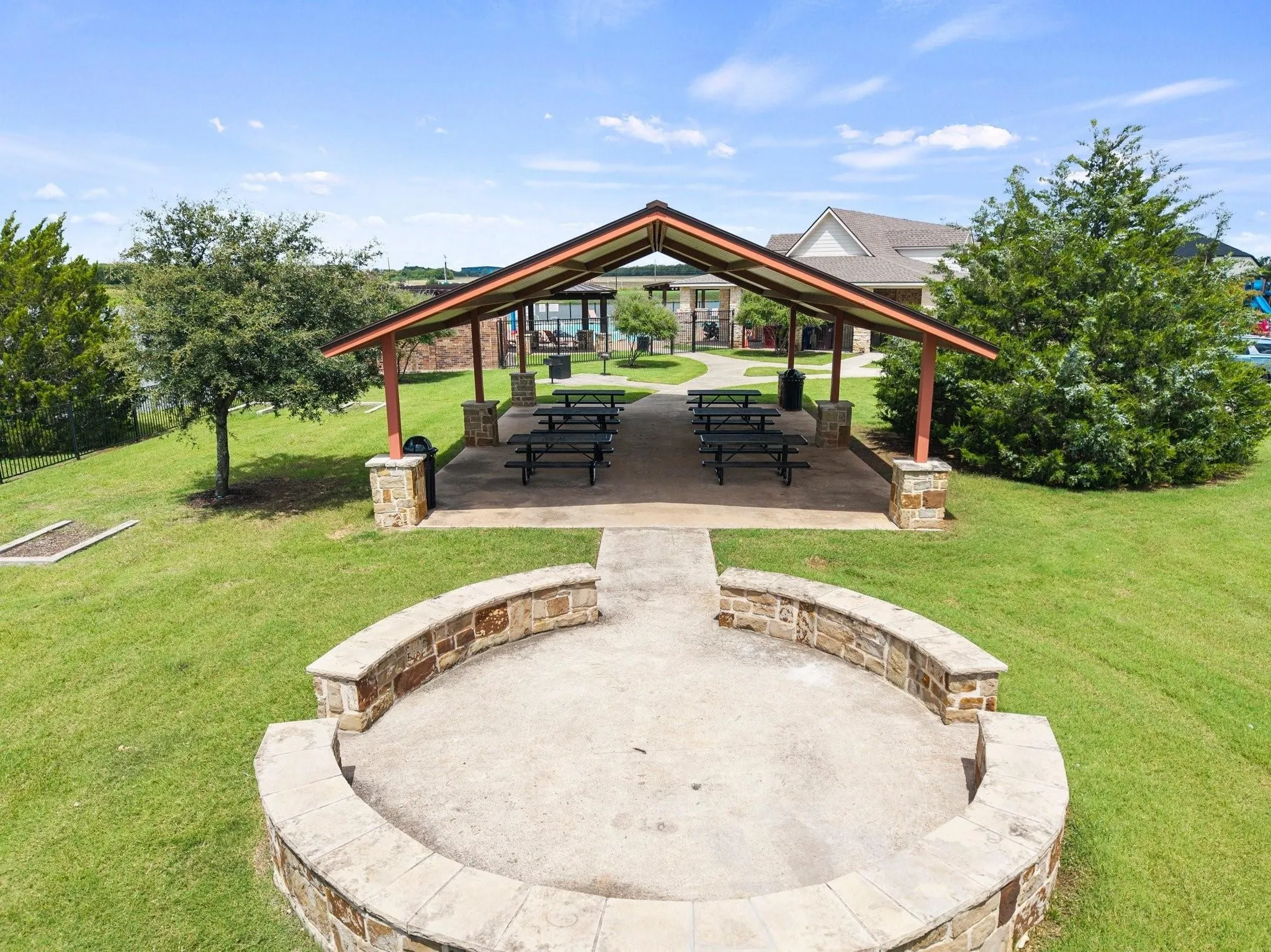 Covered outdoor pavilion with stone-clad columns, a concrete floor, and an open gable roof