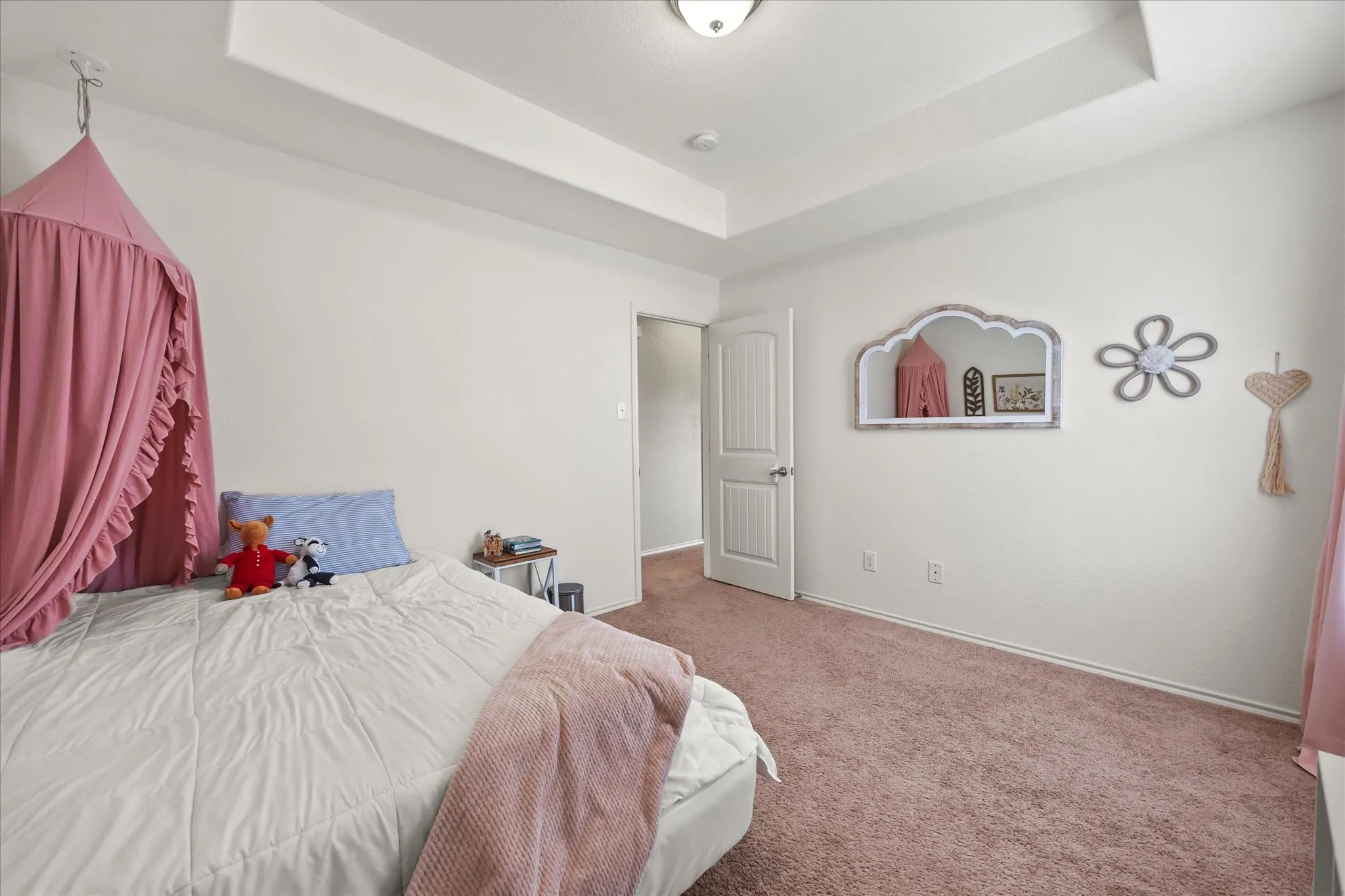 Tray ceiling, neutral wall paint, white trim, paneled door, and carpeting