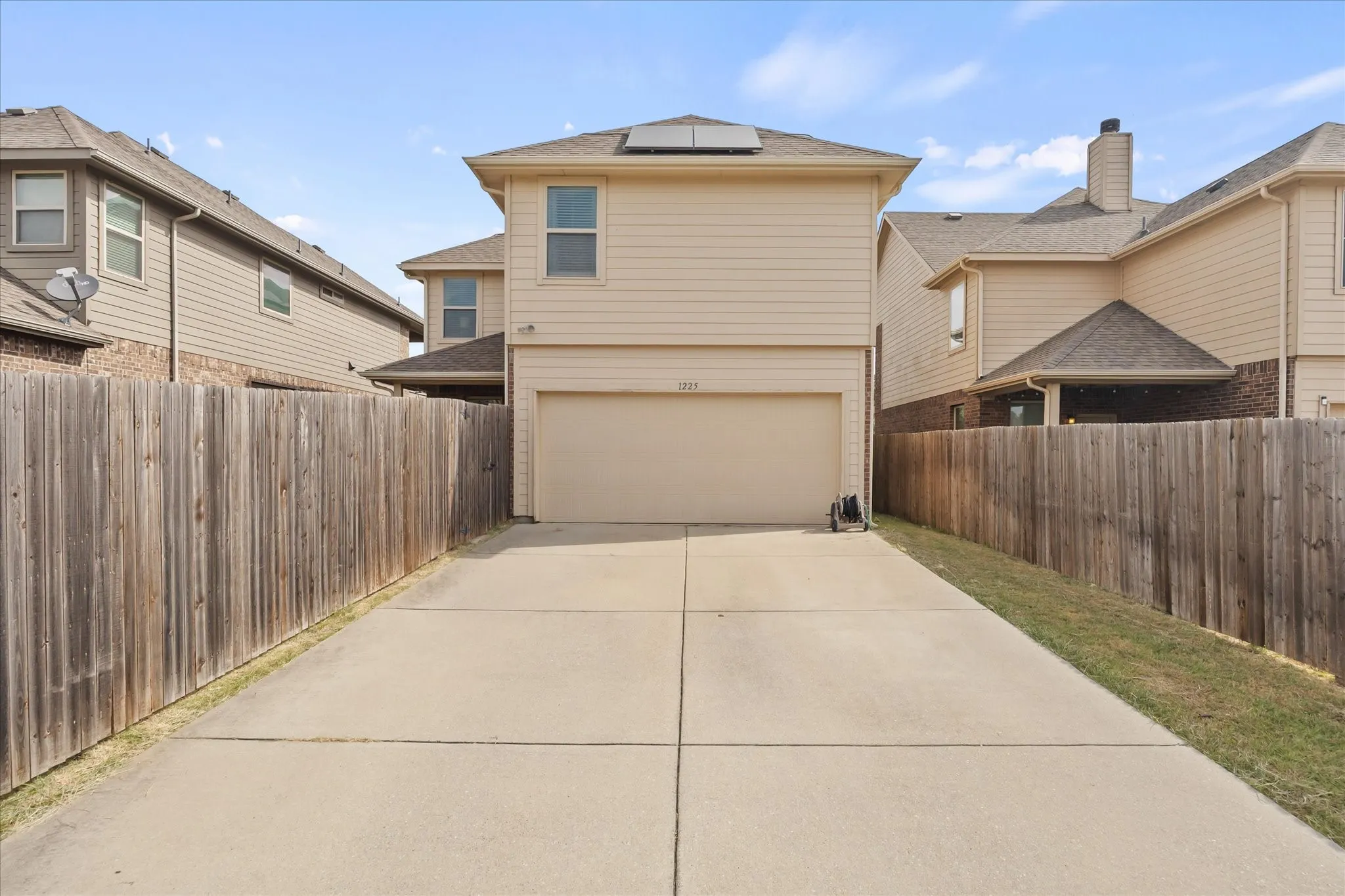 Private fenced yard featuring a concrete driveway and an attached garage