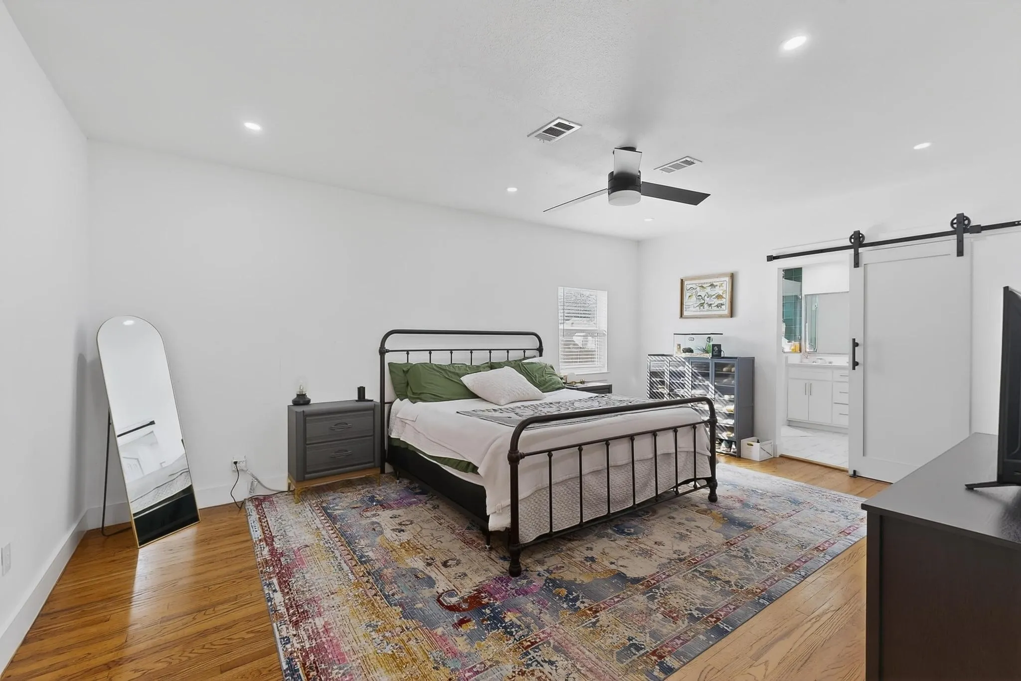 Hardwood flooring, recessed lighting, modern ceiling fan, white barn door, and a single window