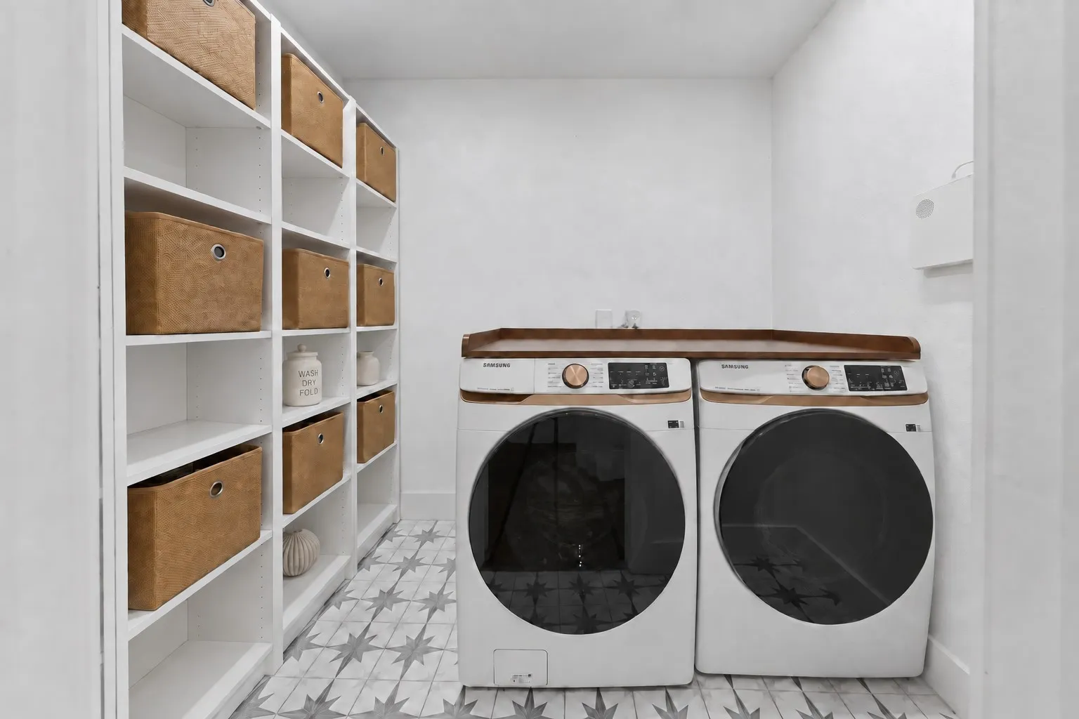 White built-in shelving, patterned floor tiling, and a wood-finish countertop