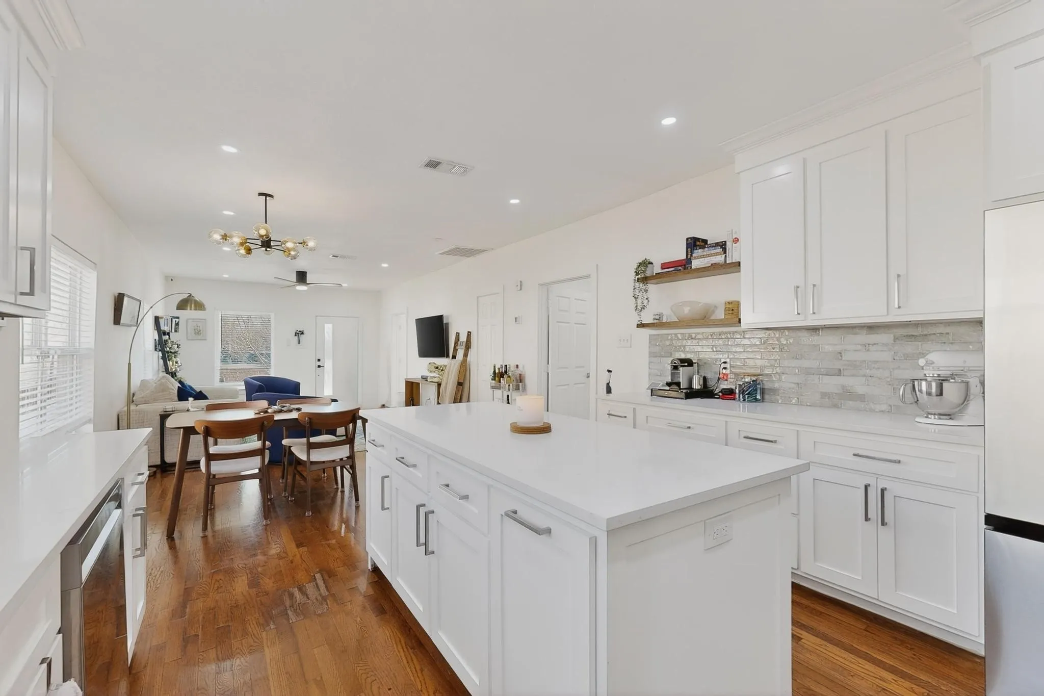 White shaker cabinetry with modern hardware, light-toned countertops, and a tiled backsplash