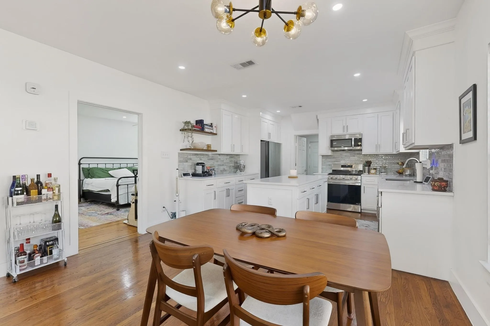 Hardwood flooring, recessed lighting, white cabinetry, stainless steel appliances, and a central kitchen island