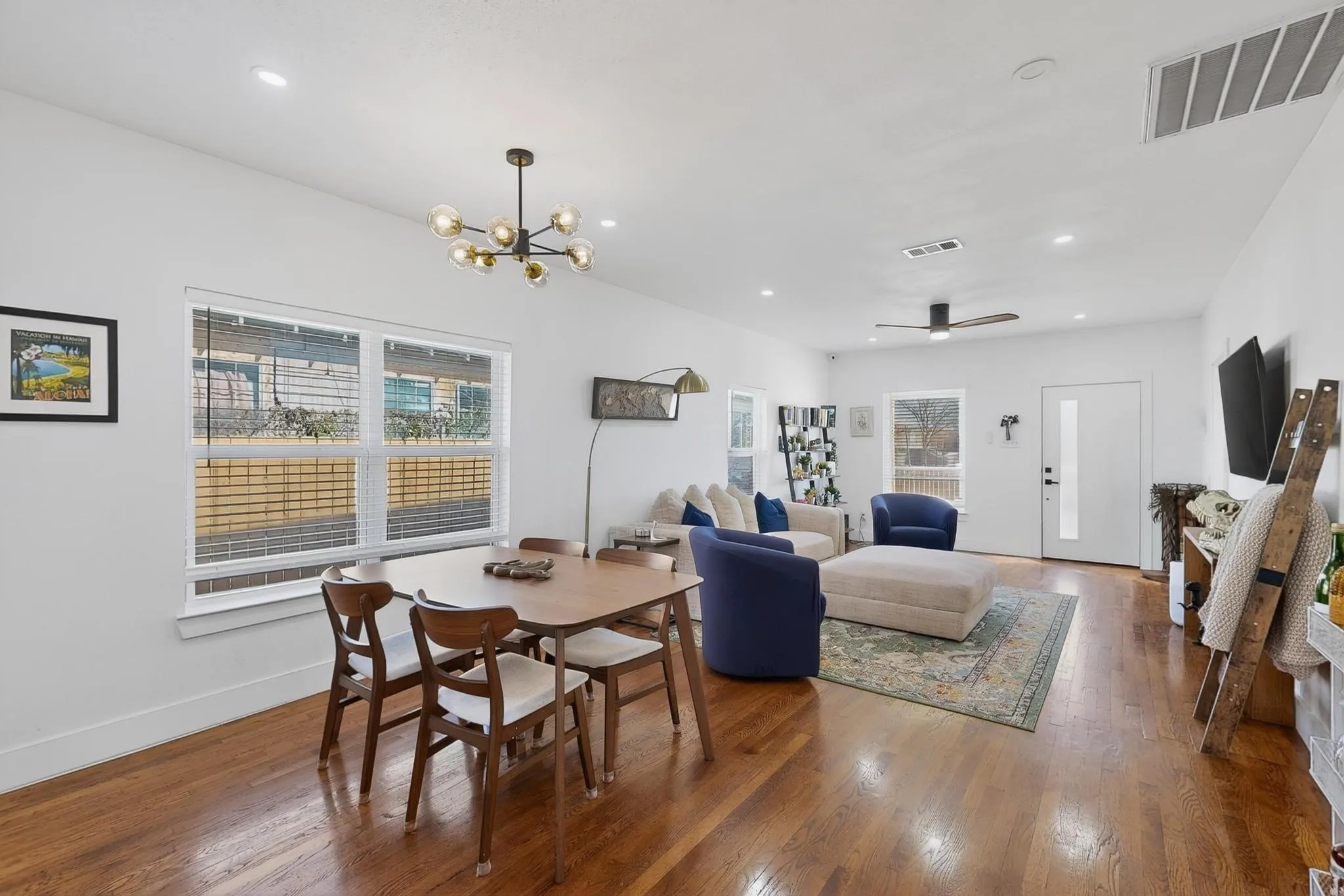 Open-concept living space featuring wood-finish flooring, recessed lighting, and a contemporary chandelier