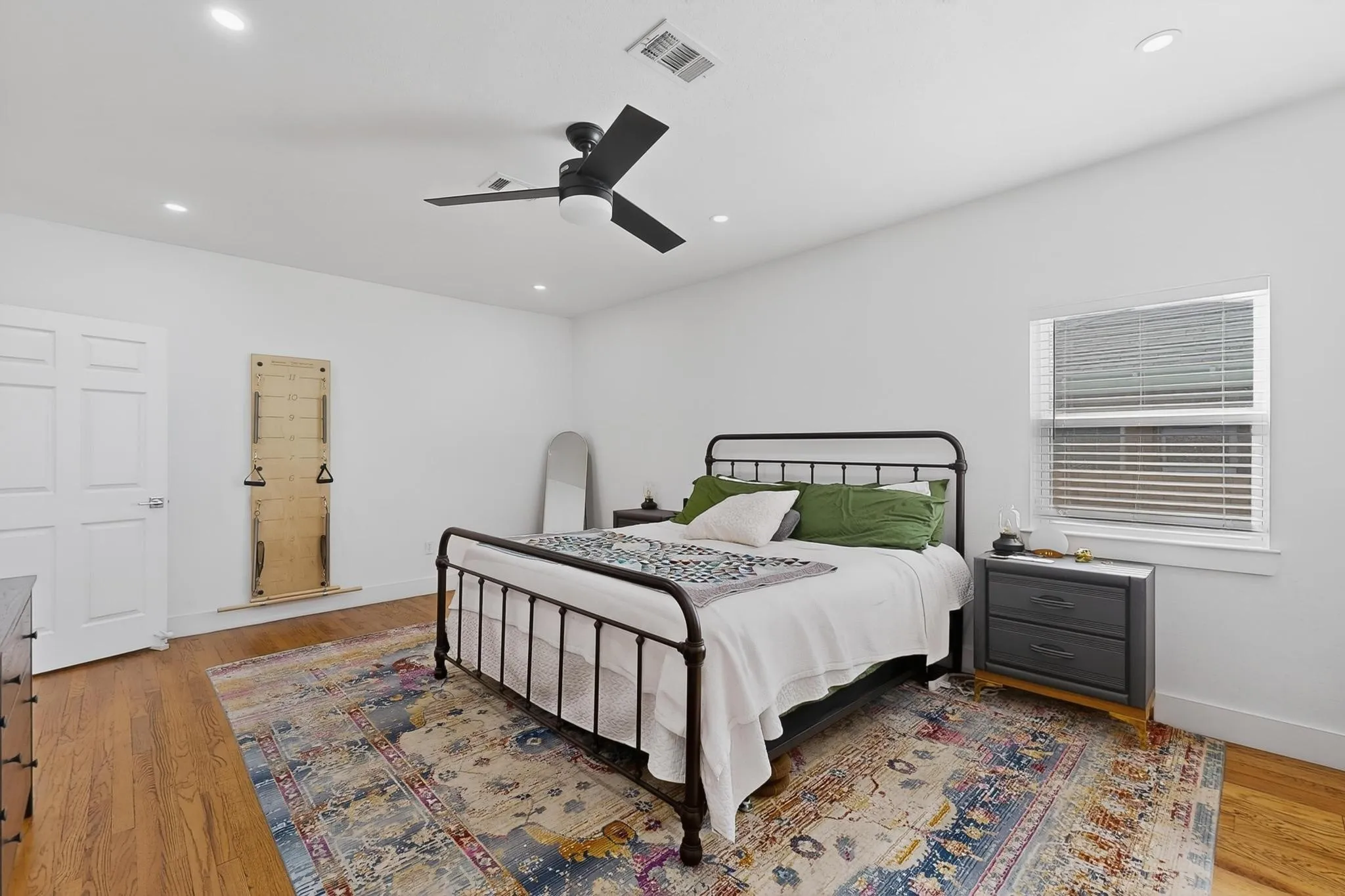Hardwood flooring, recessed lighting, ceiling fan, white paneled door, and window with blinds