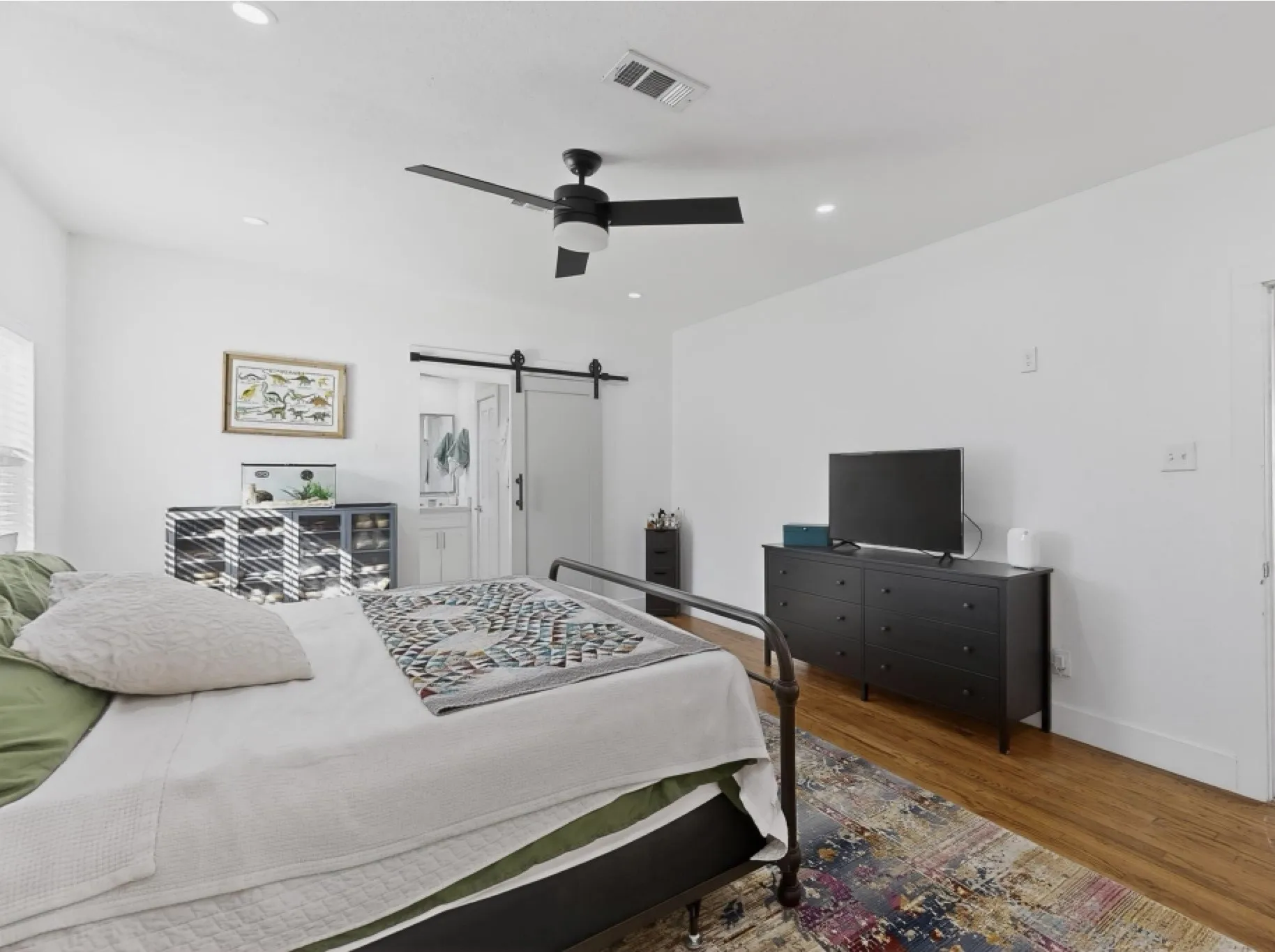 Recessed lighting, wood-finish flooring, ceiling fan, white walls, and a sliding barn door