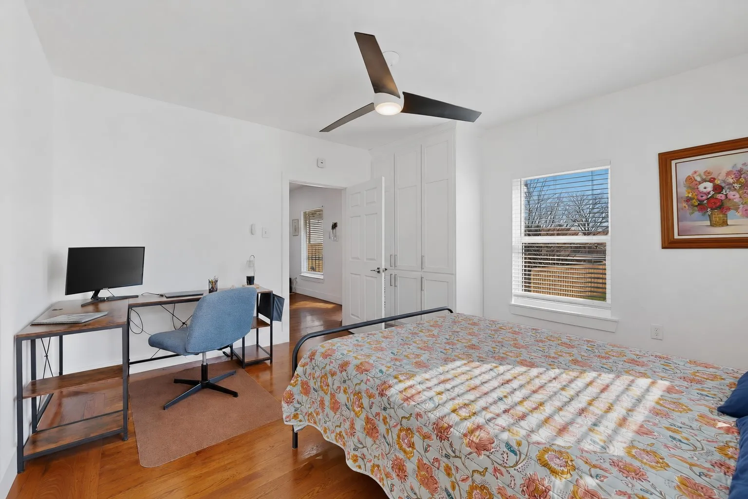 Hardwood-style flooring throughout with a ceiling fan, a window with blinds, and built-in white cabinetry