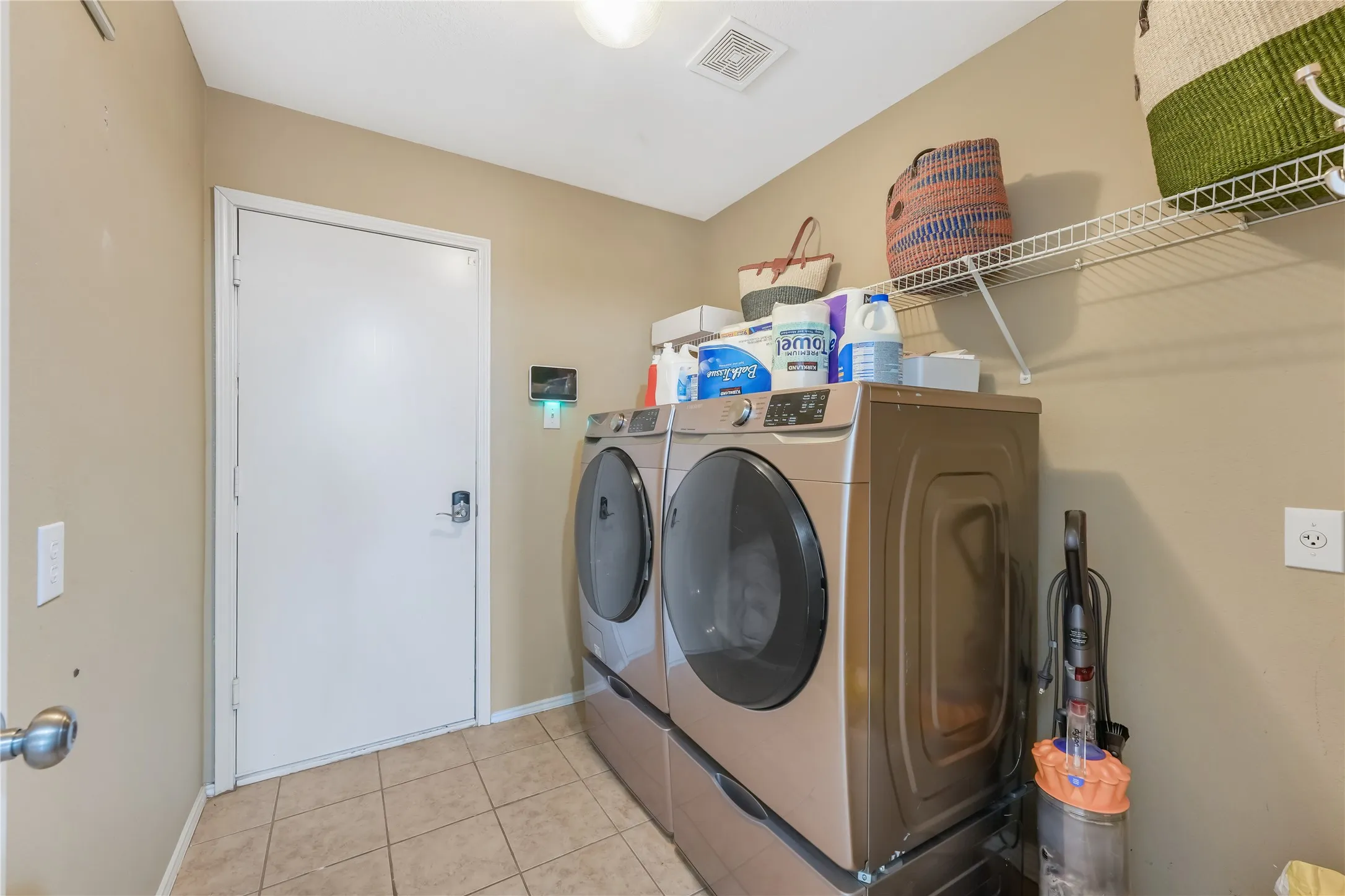 Laundry area featuring tiled flooring, a built-in wire shelving unit, and a flush-mount ceiling light