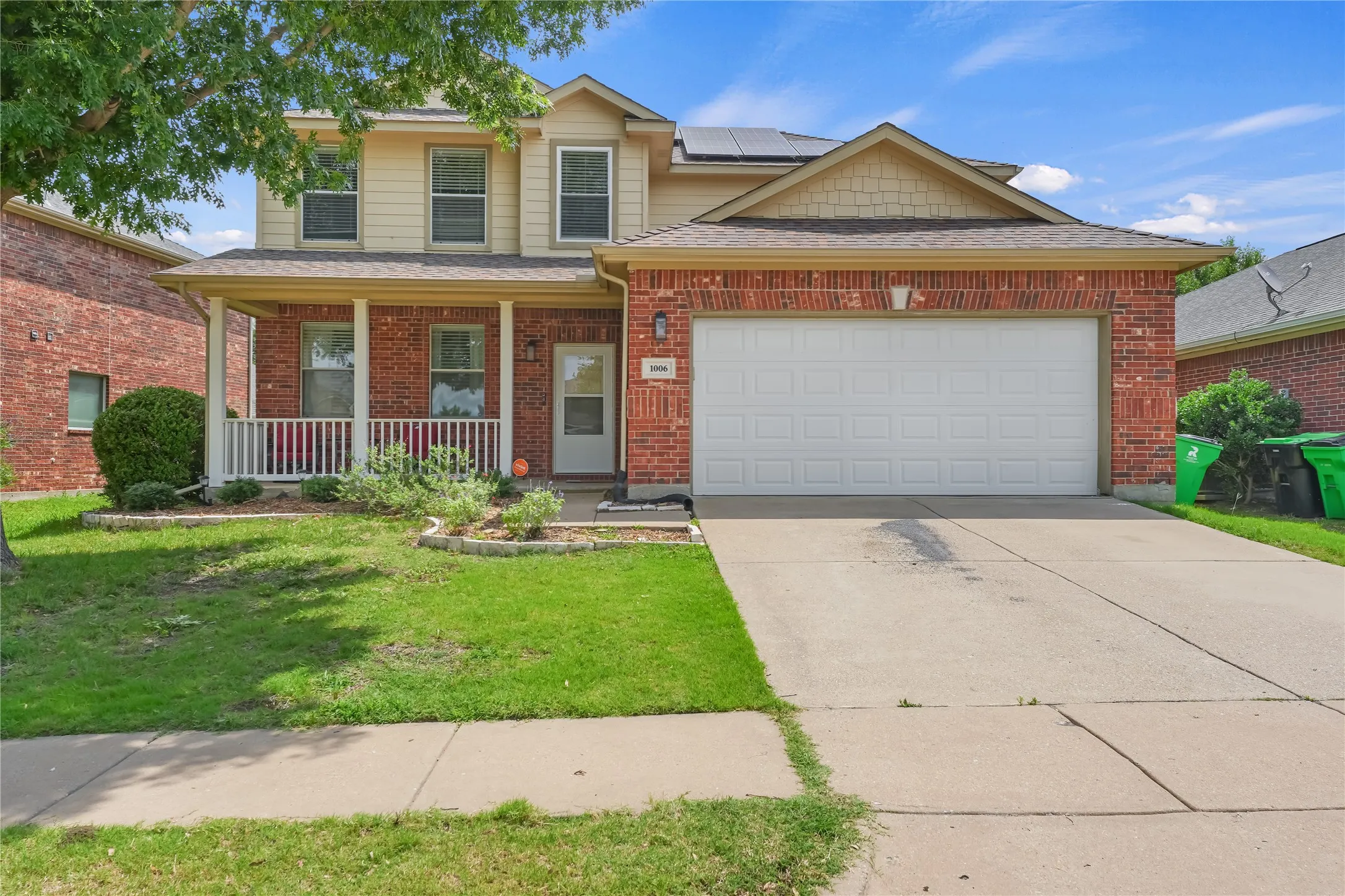 Brick and siding exterior with a covered porch, two-car garage, and concrete driveway