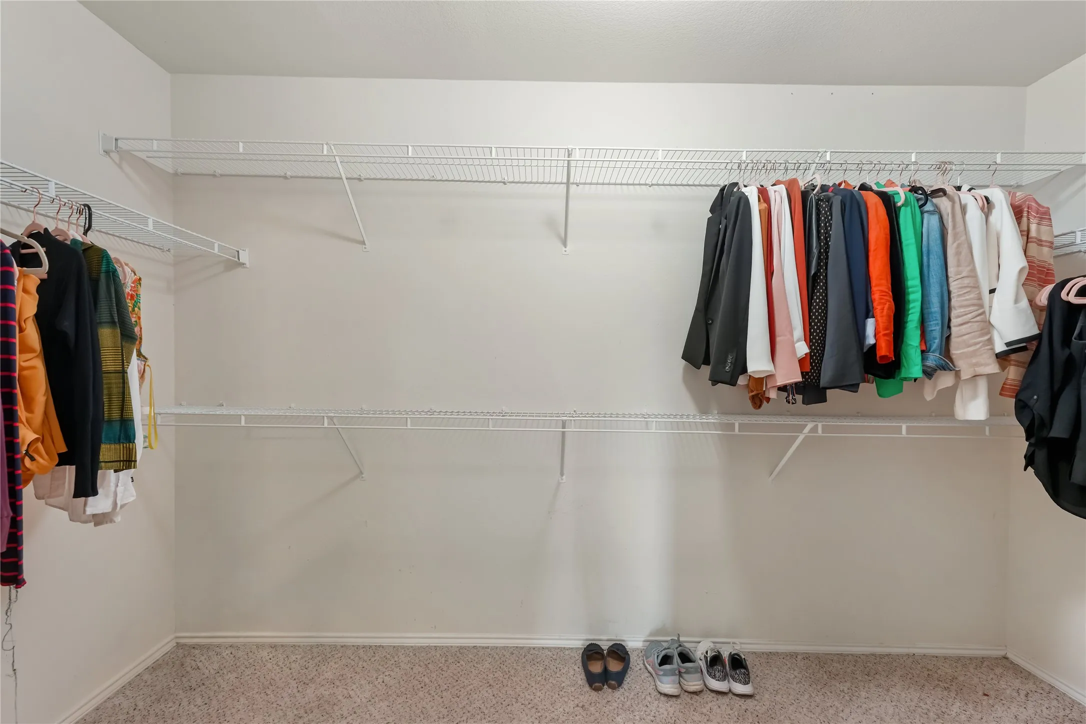 Carpeted closet featuring white wire shelving and hanging rods