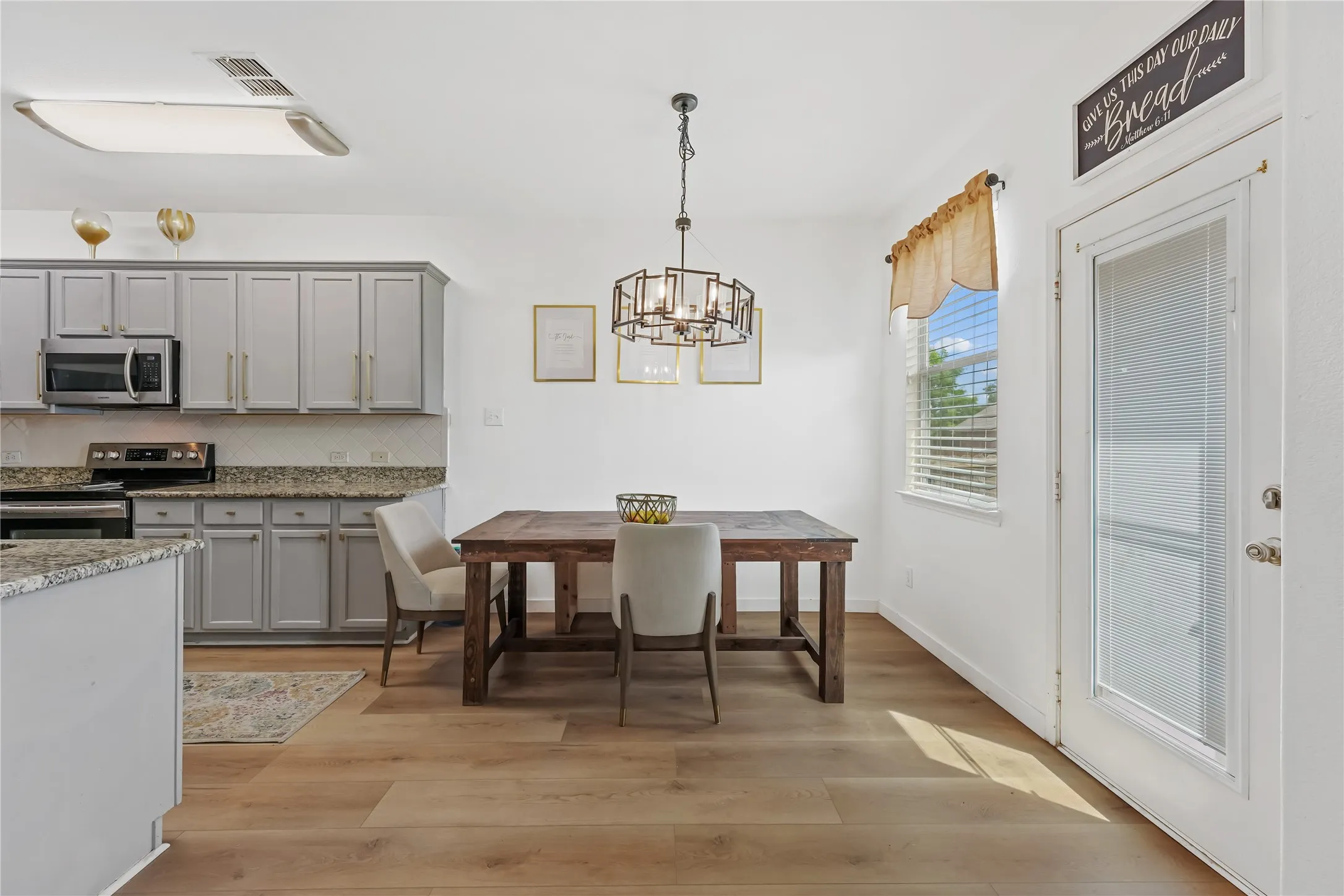 Kitchen with gray cabinetry, granite countertops, stainless steel appliances, and wood-finish flooring