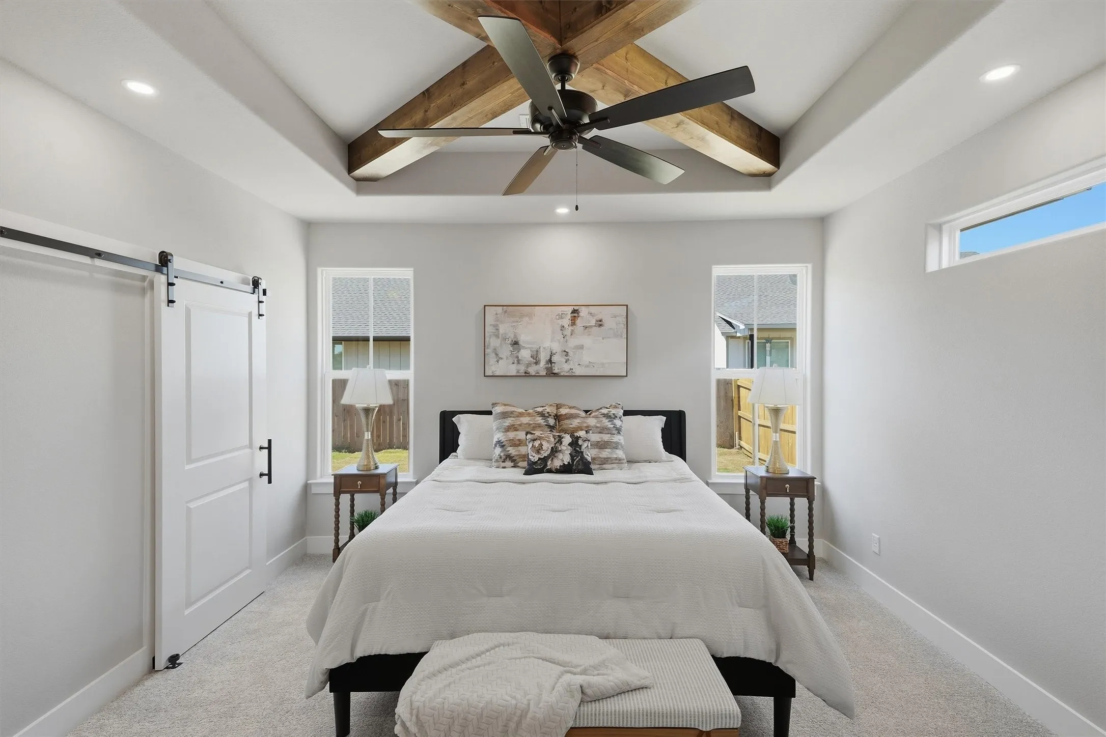 Vaulted ceiling with wood-finish beams and a ceiling fan, recessed lighting, white barn door, and dual windows