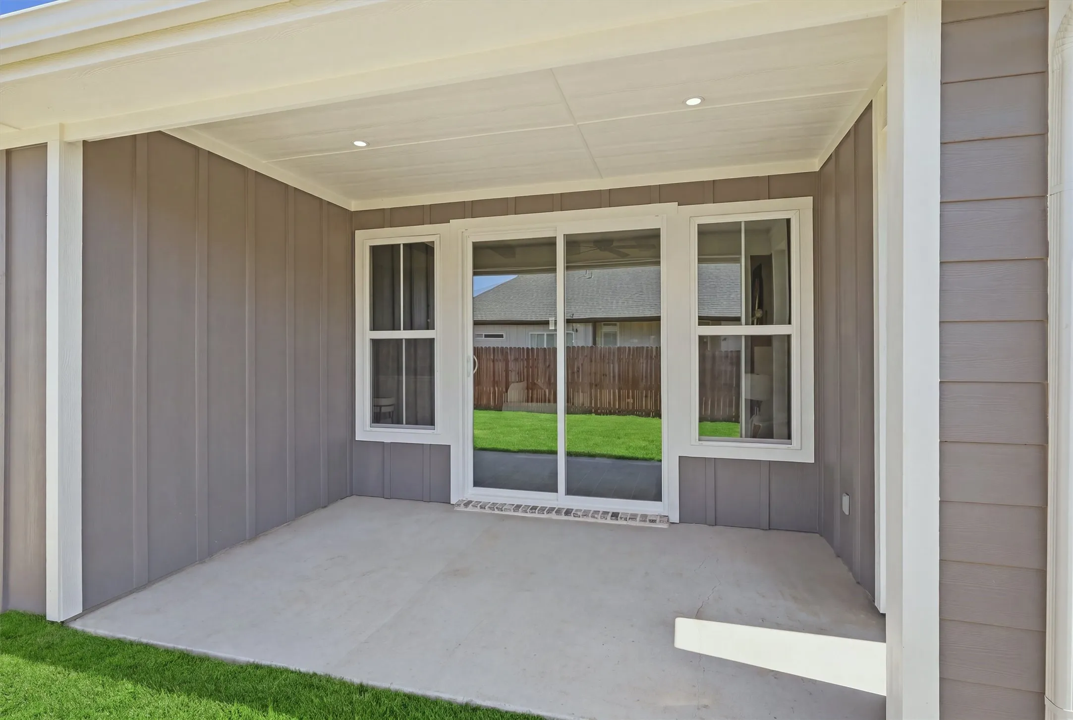 Covered patio featuring a concrete surface, overhead lighting, and board and batten siding