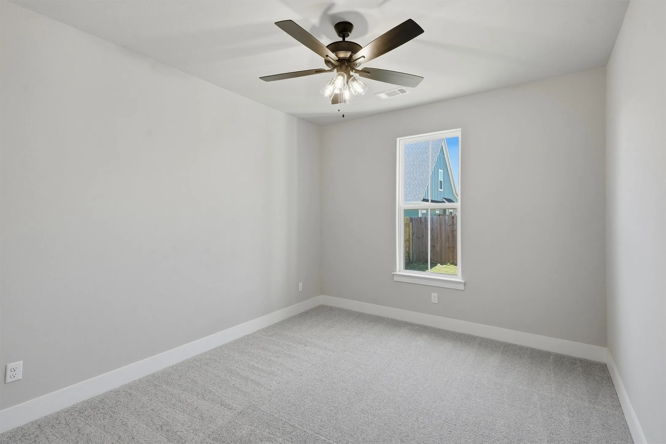 Neutral wall paint, ceiling fan with integrated lighting, window with white trim, and gray carpeting