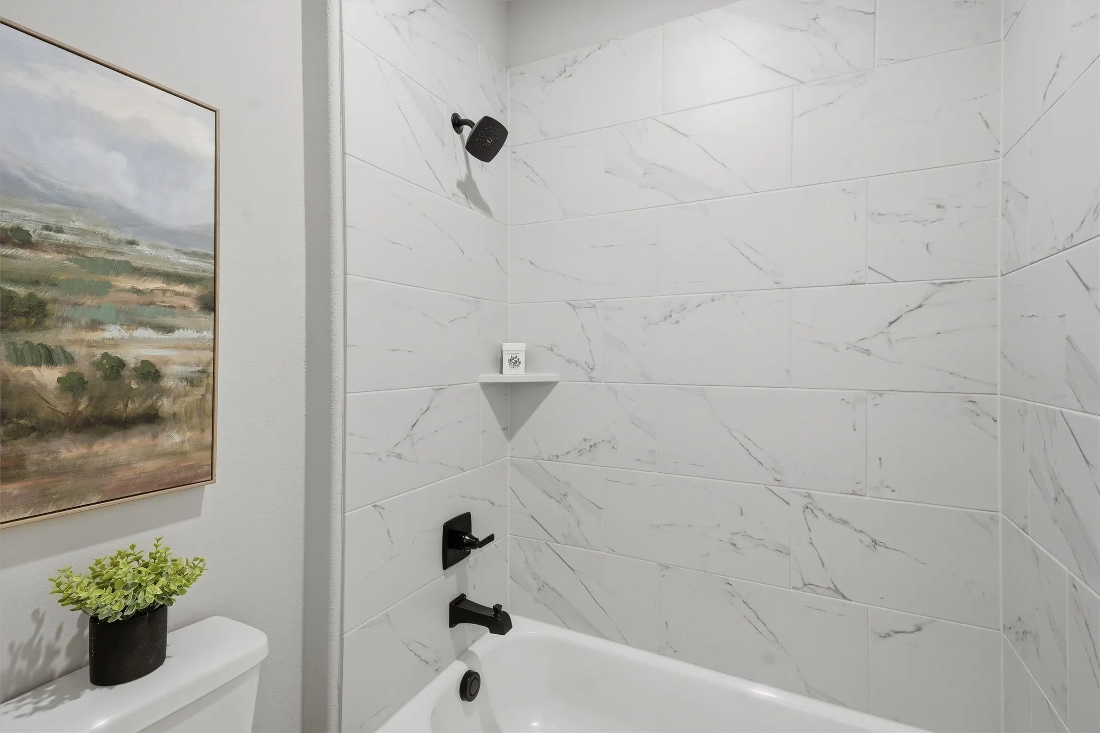White subway tile shower surround with integrated shelf and matte black fixtures