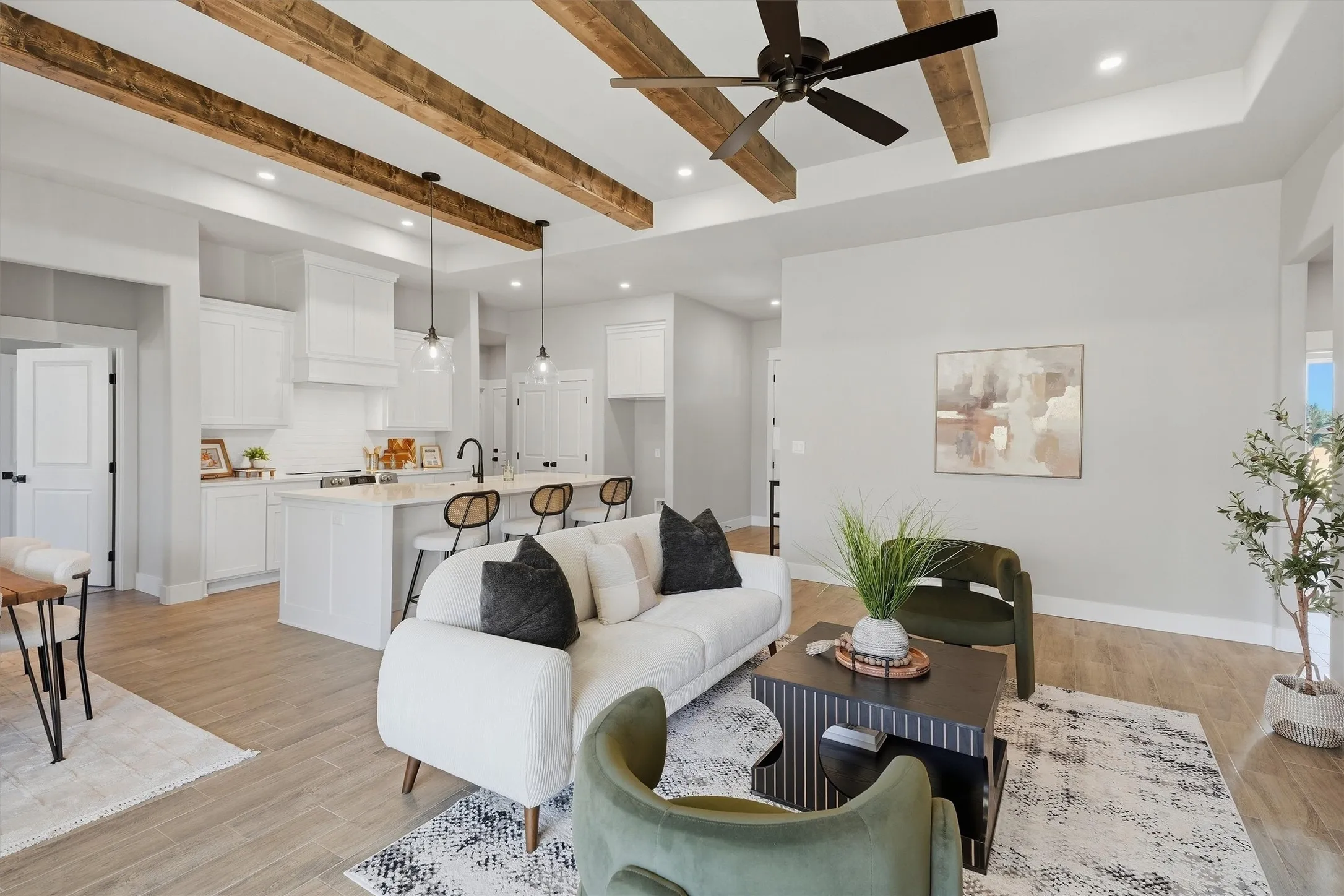 Exposed wood ceiling beams, wood-finish flooring, recessed lighting, ceiling fan, kitchen island with seating