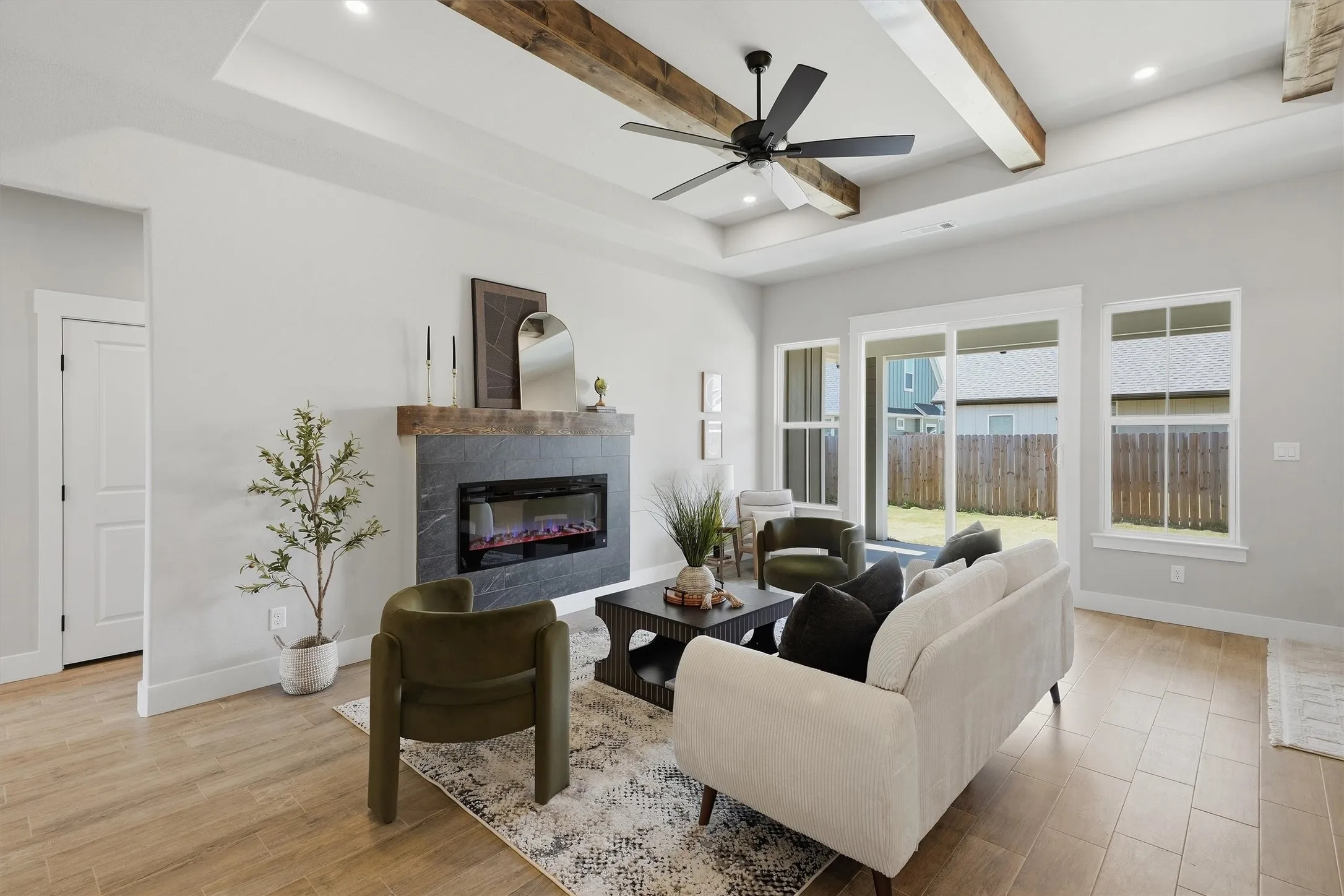 Tray ceiling with exposed wood-finish beams, recessed lighting, and a ceiling fan
