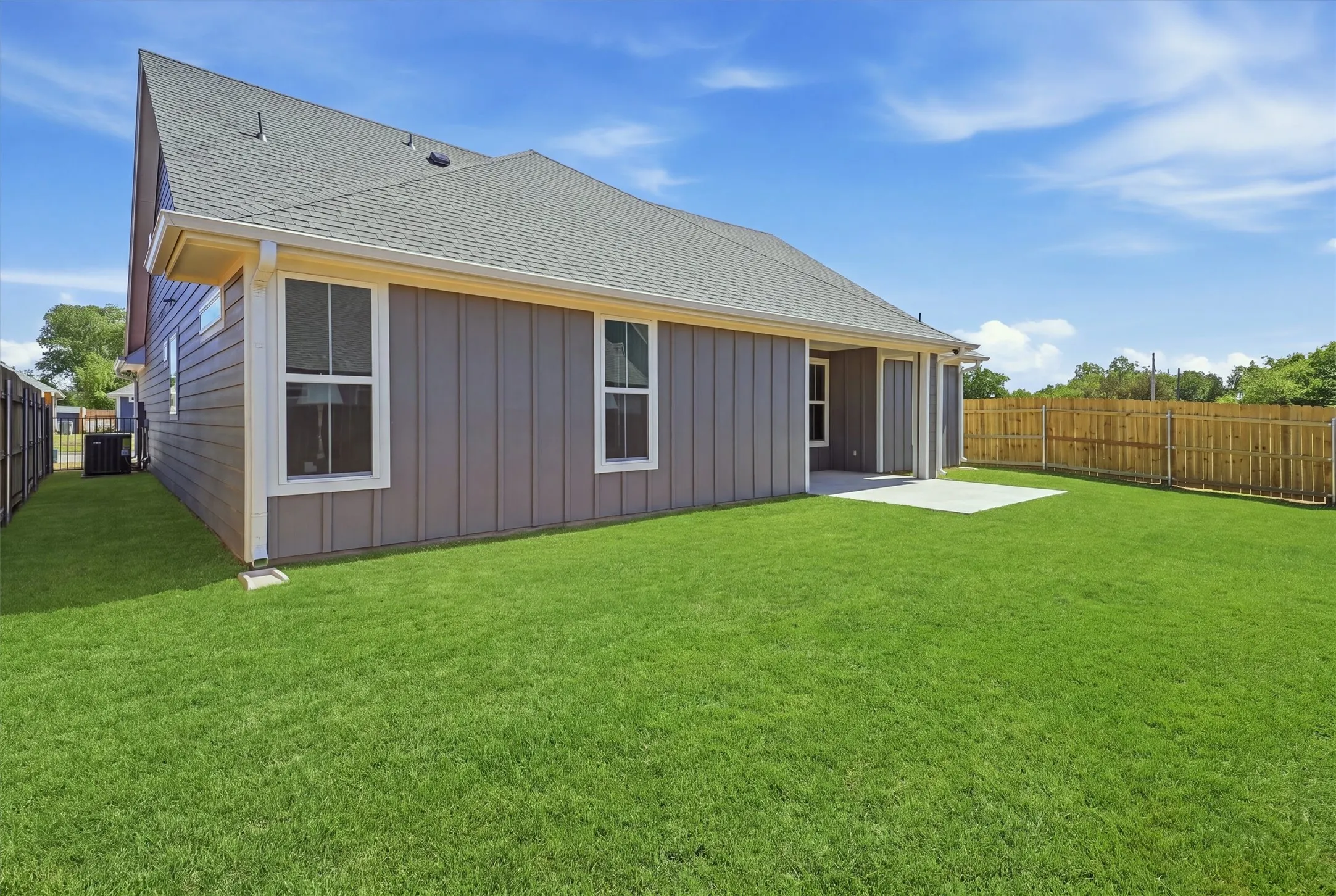 Expansive green lawn with a privacy fence and concrete patio