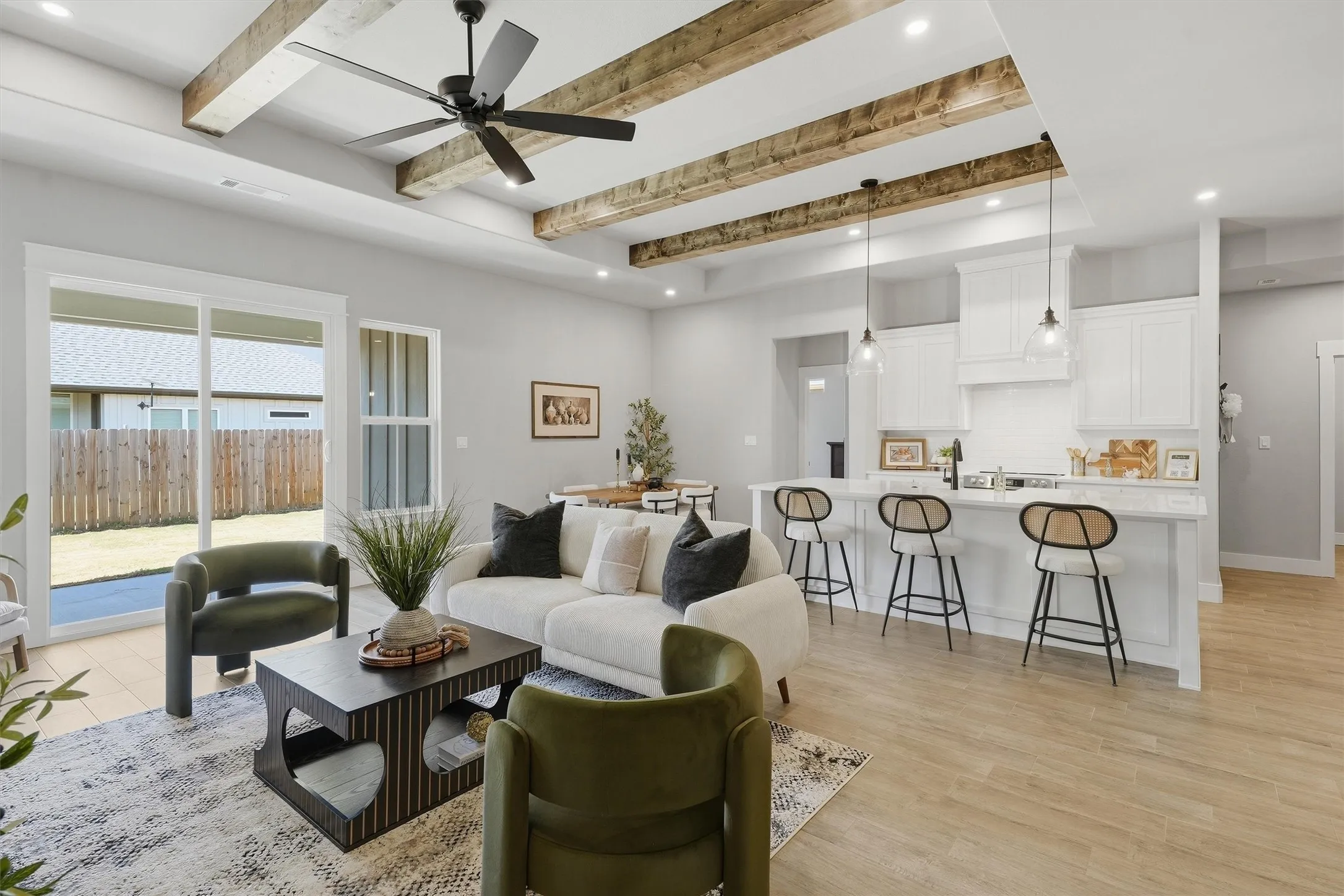 Tray ceiling with exposed wood beams, recessed lighting, wood-finish flooring, white shaker cabinetry, and a kitchen island with seating