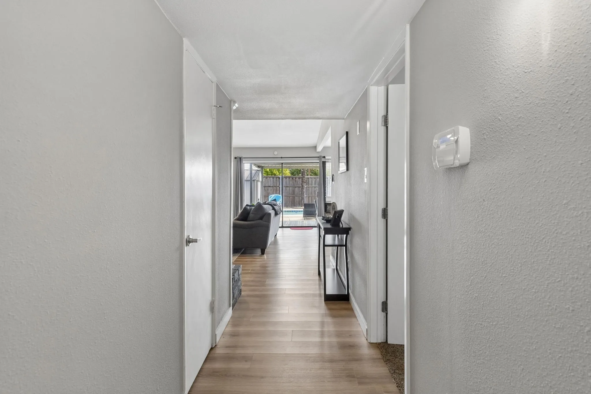 A Clear View to the Outdoors - Laminate flooring carries the eye from the entry toward the family room, where sliding glass doors create an inviting sightline all the way to the backyard and pool.