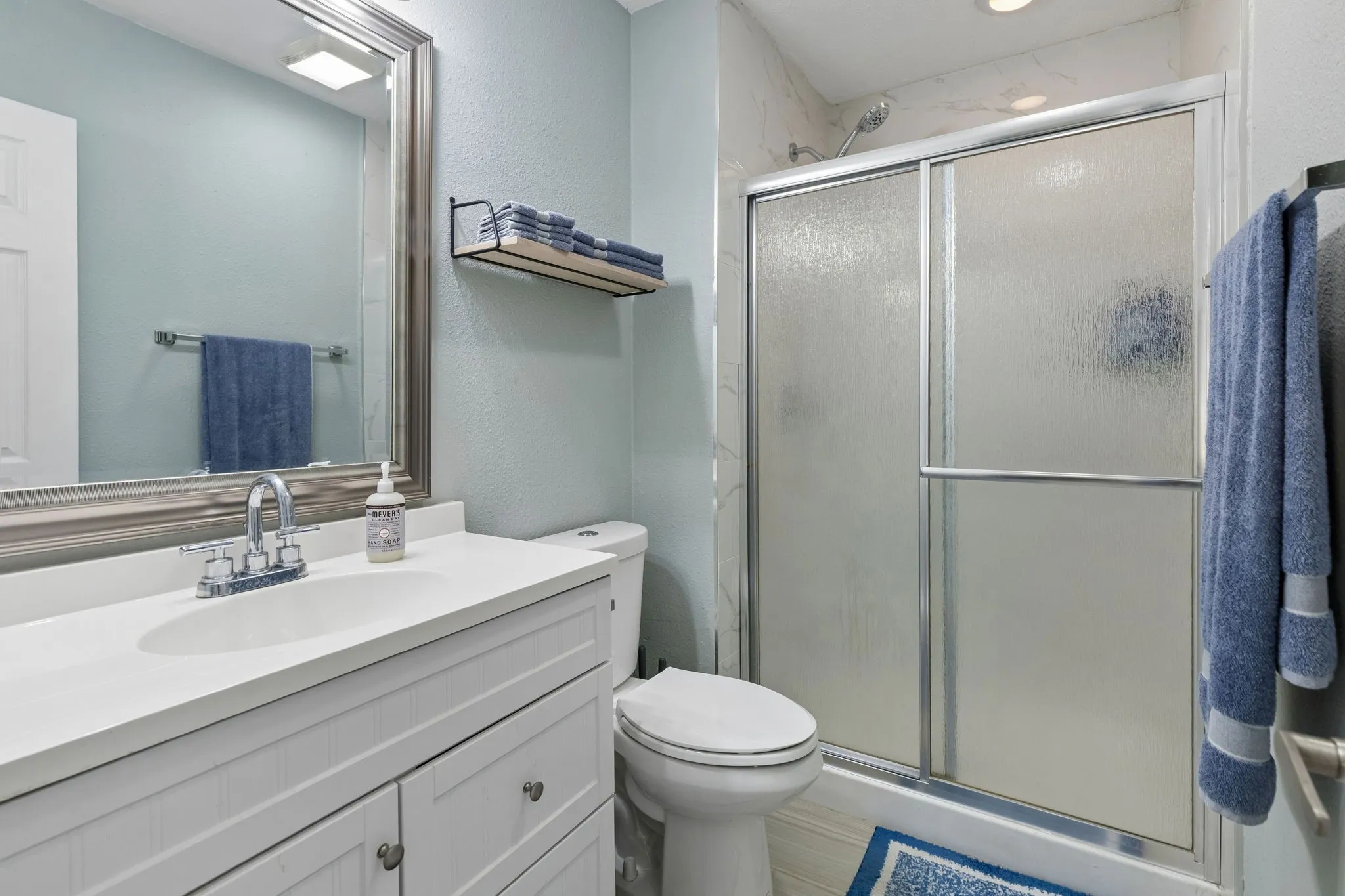 Freshly Updated Primary Bath - An updated vanity, framed mirror, refreshed fixtures, and updated walk-in shower surround give the primary bath a clean, contemporary look.