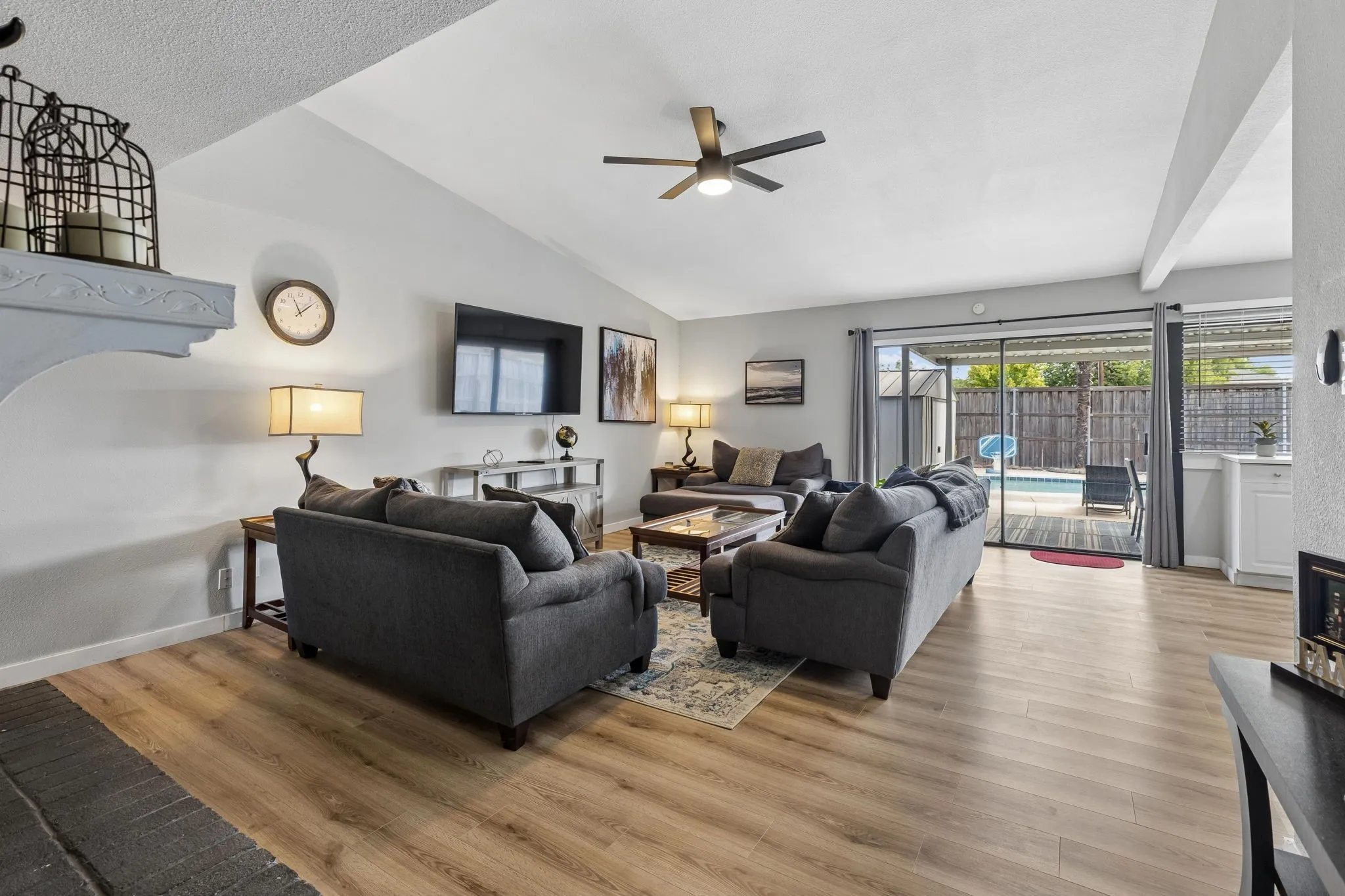 Vaulted Living with an Outdoor Connection - A soaring vaulted ceiling adds volume to the family room, while the brick-surround wood-burning fireplace brings architectural character and sliding glass doors extend the living space toward the patio and pool.