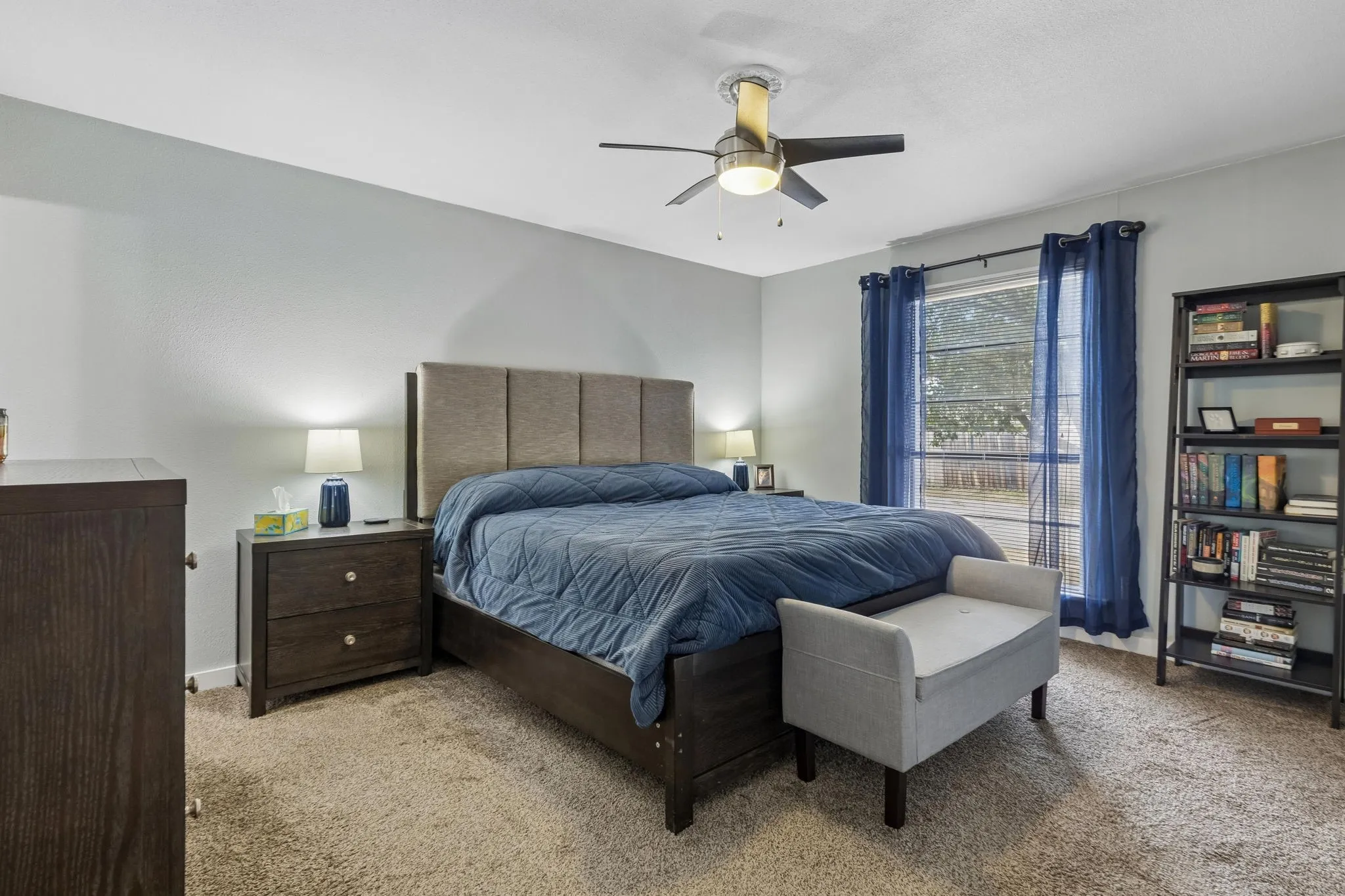 Comfortable Primary Retreat - Soft carpeting, a ceiling fan, and a large window create a comfortable primary bedroom with plenty of natural light and room to unwind.