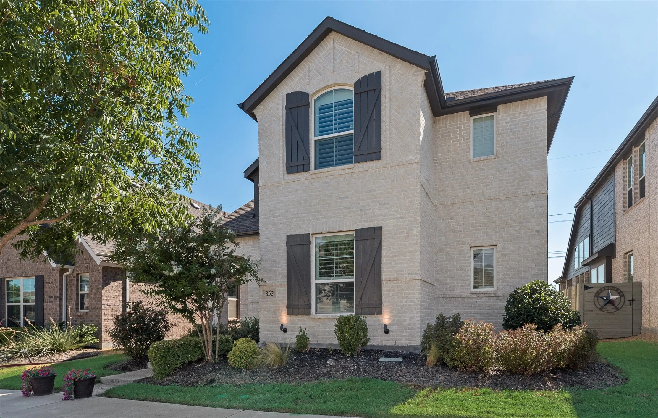 Brick exterior with dark shutters, arched window, and landscaped front yard