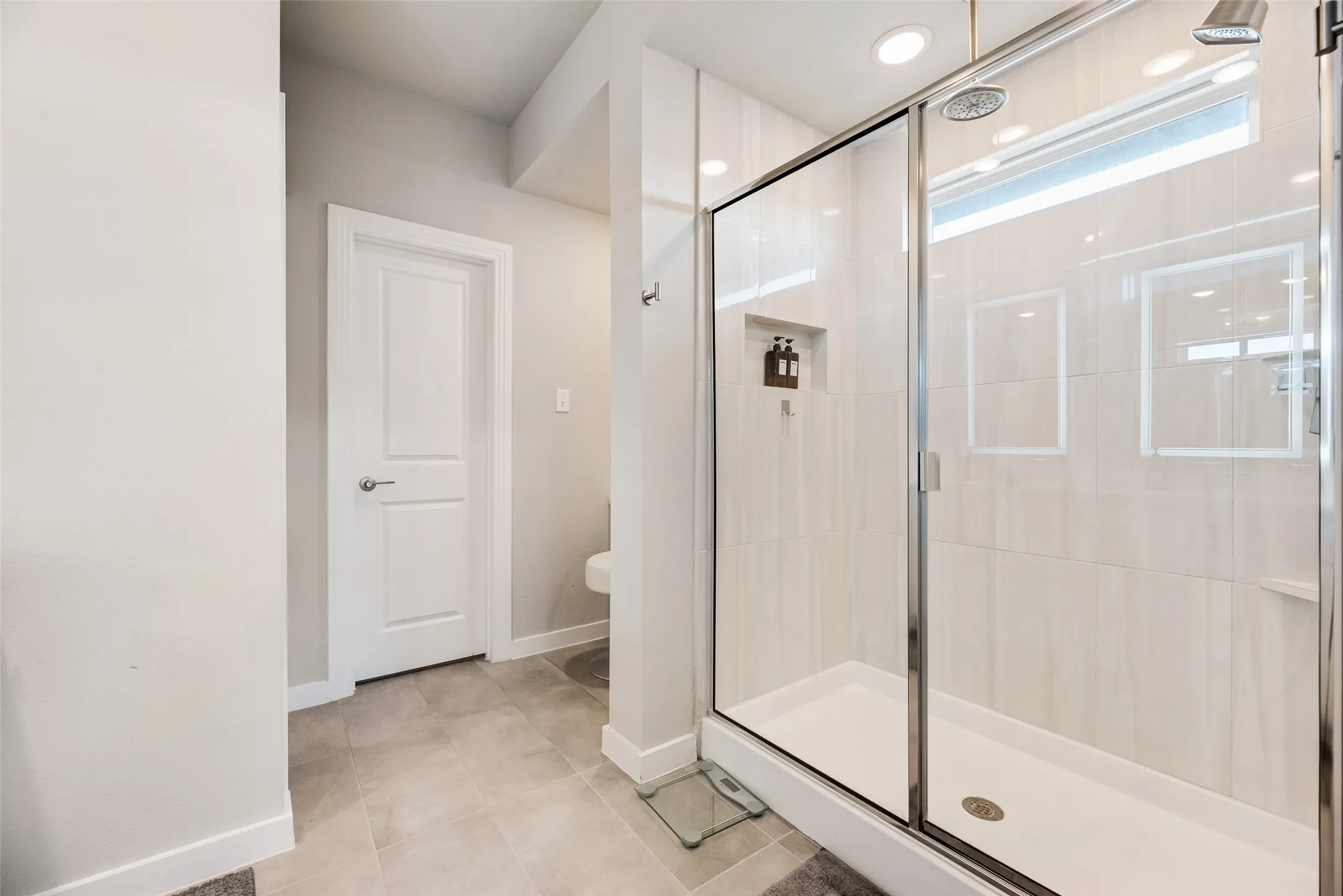 Glass-enclosed shower with a recessed niche, dual shower heads, and transom window