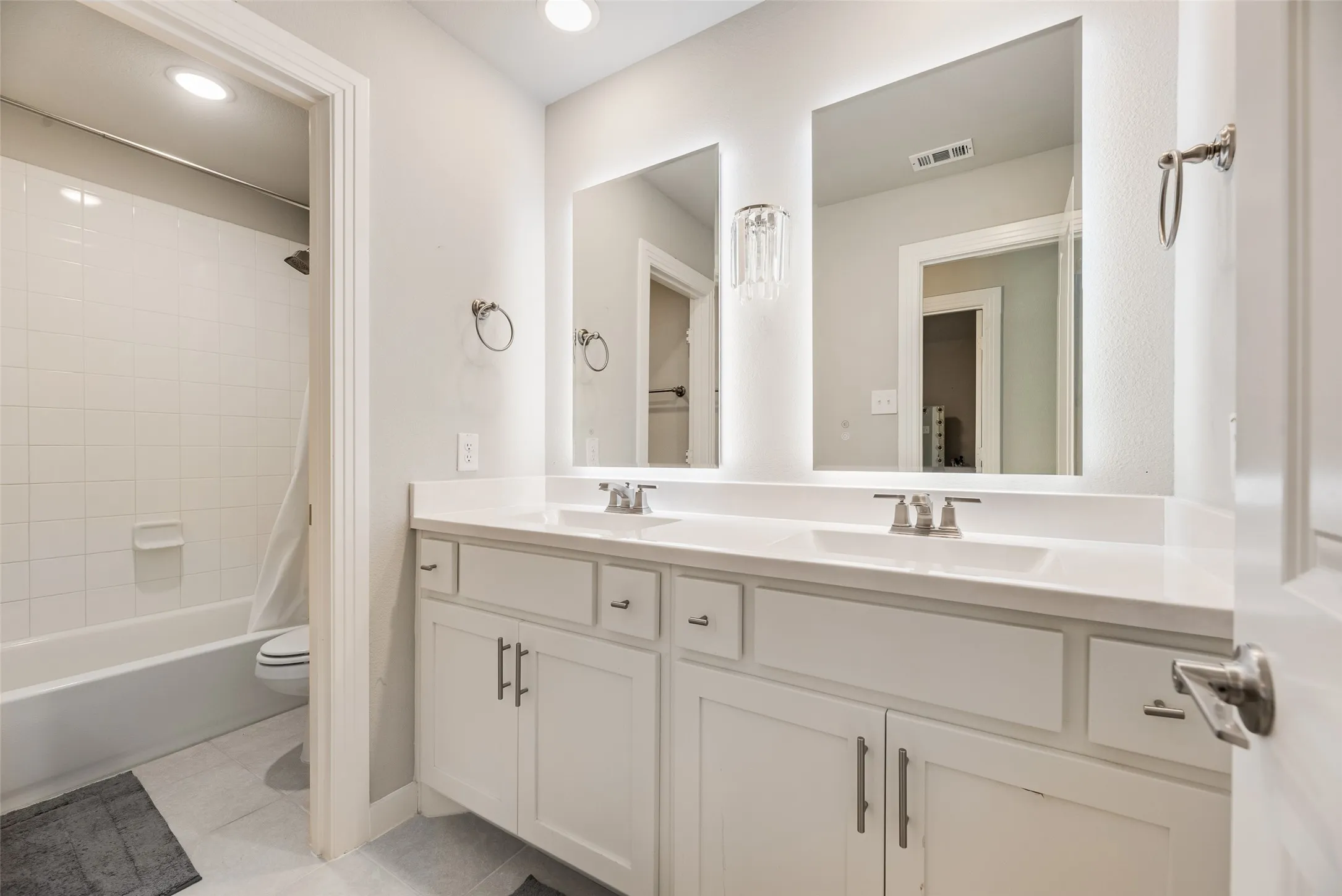 Dual vanity with white cabinetry and integrated sinks, complemented by contemporary wall-mounted light fixtures