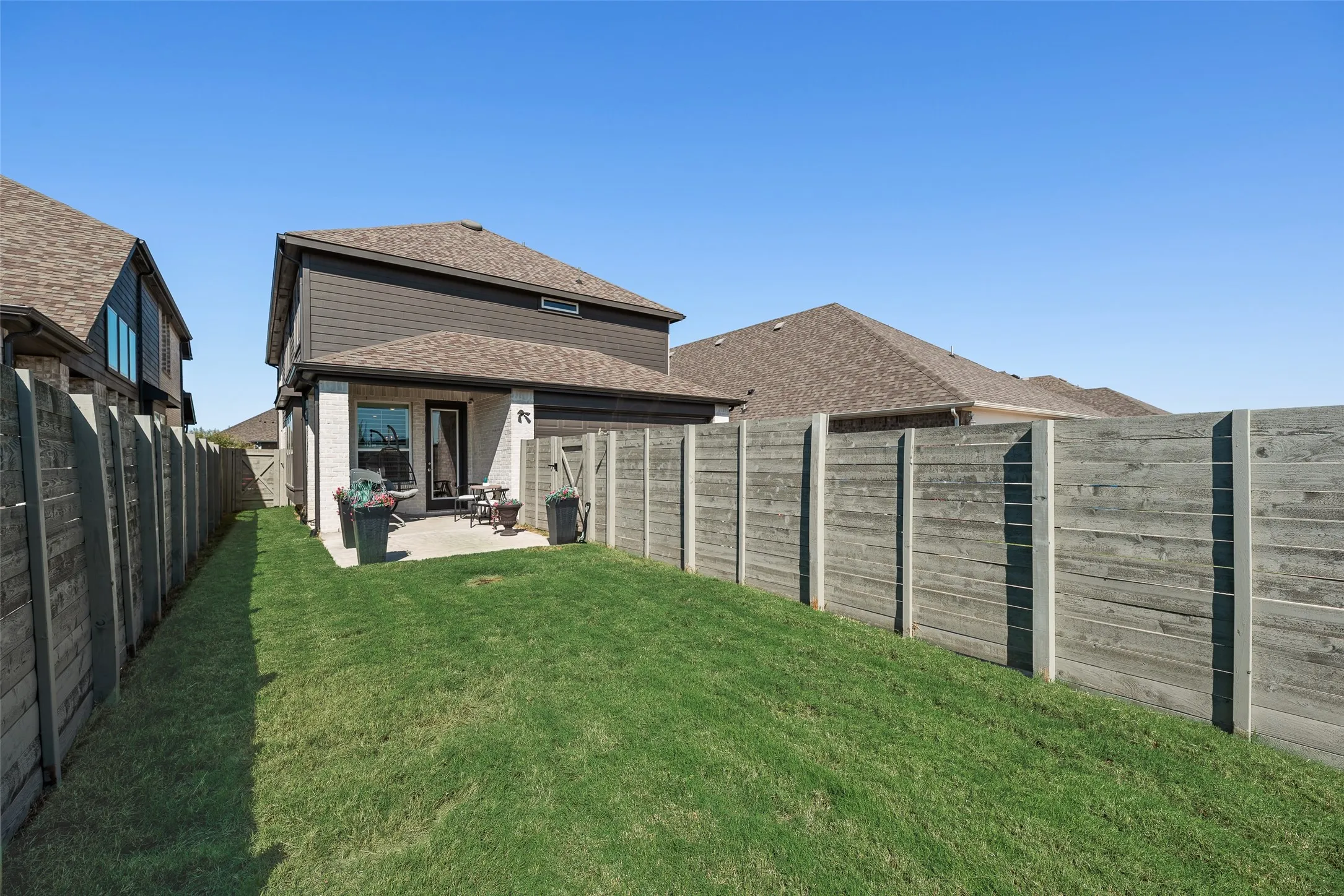 Expansive backyard featuring a manicured lawn, concrete patio, and a privacy fence