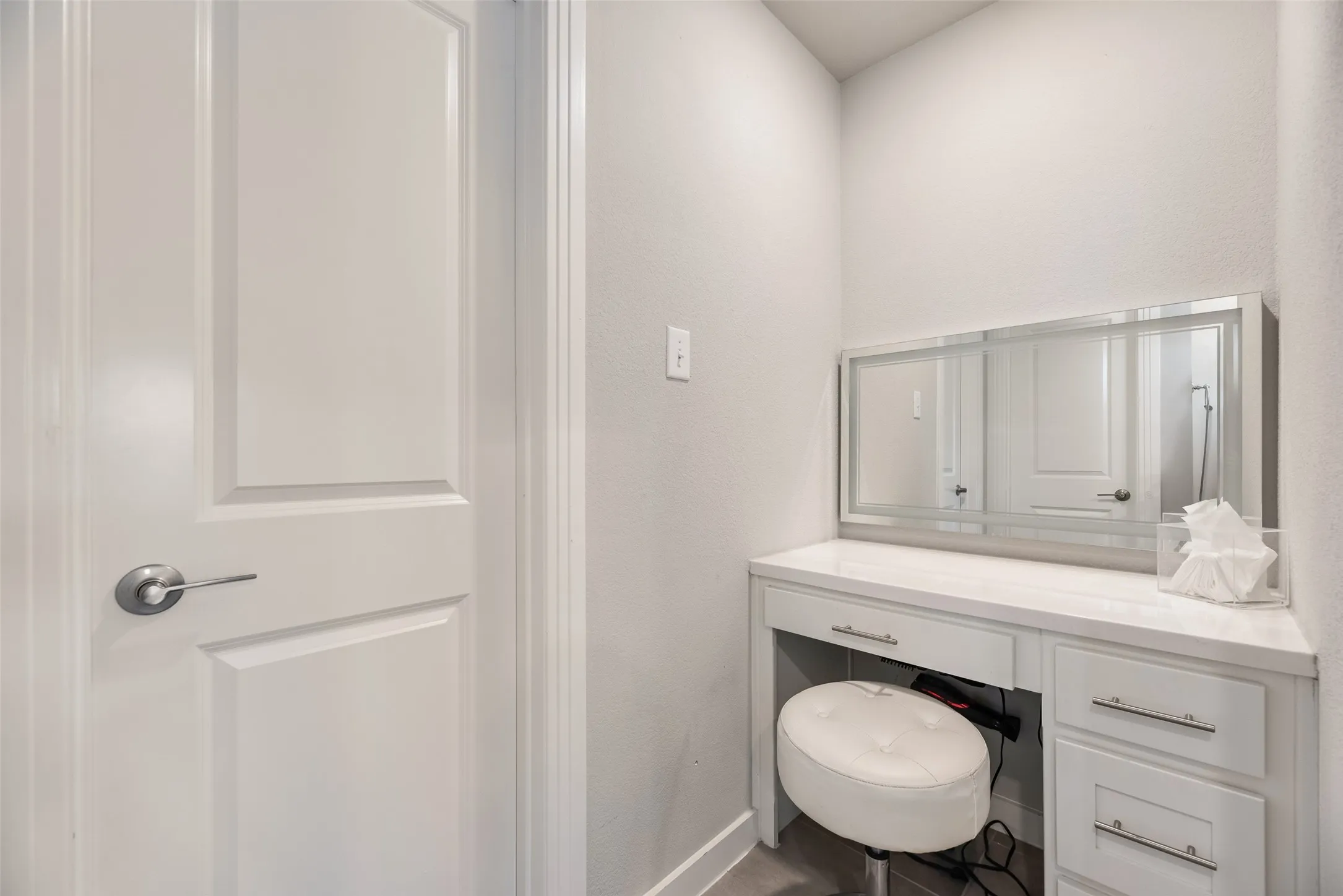 Built-in vanity with a marble-finish countertop, integrated drawers, and a large wall-mounted mirror