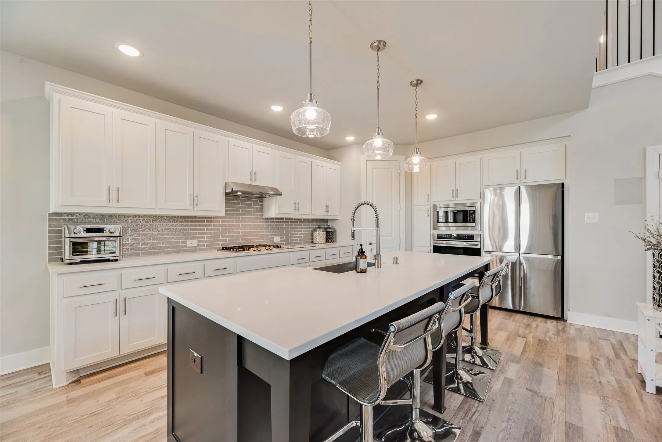Gourmet kitchen with white cabinetry, stainless steel appliances, a center island with countertop seating, and wood-finish flooring