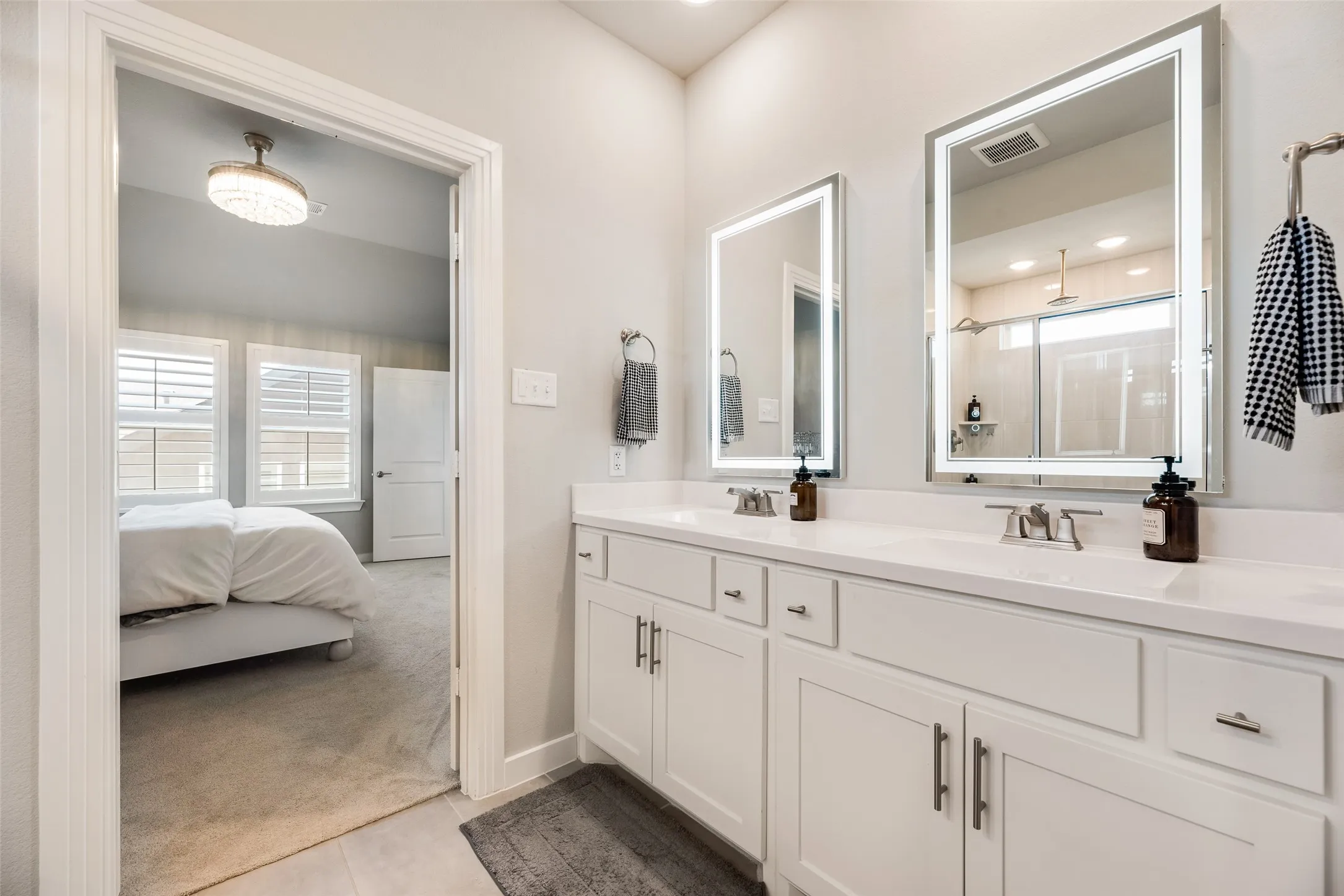 Dual vanity with undermount sinks, illuminated mirrors, and white cabinetry