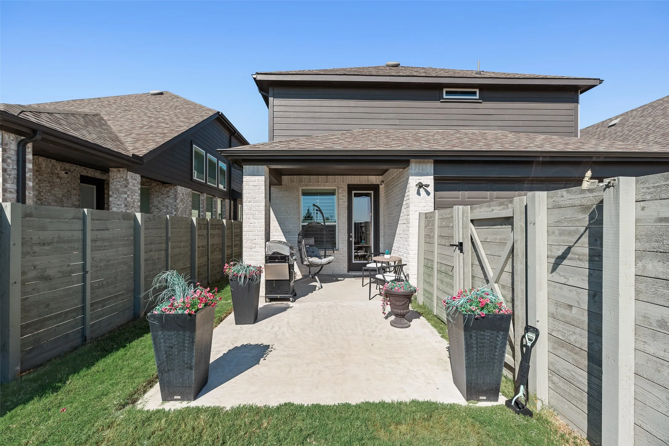 Expansive concrete patio with covered awning, private wood-style fencing, and a rear entrance