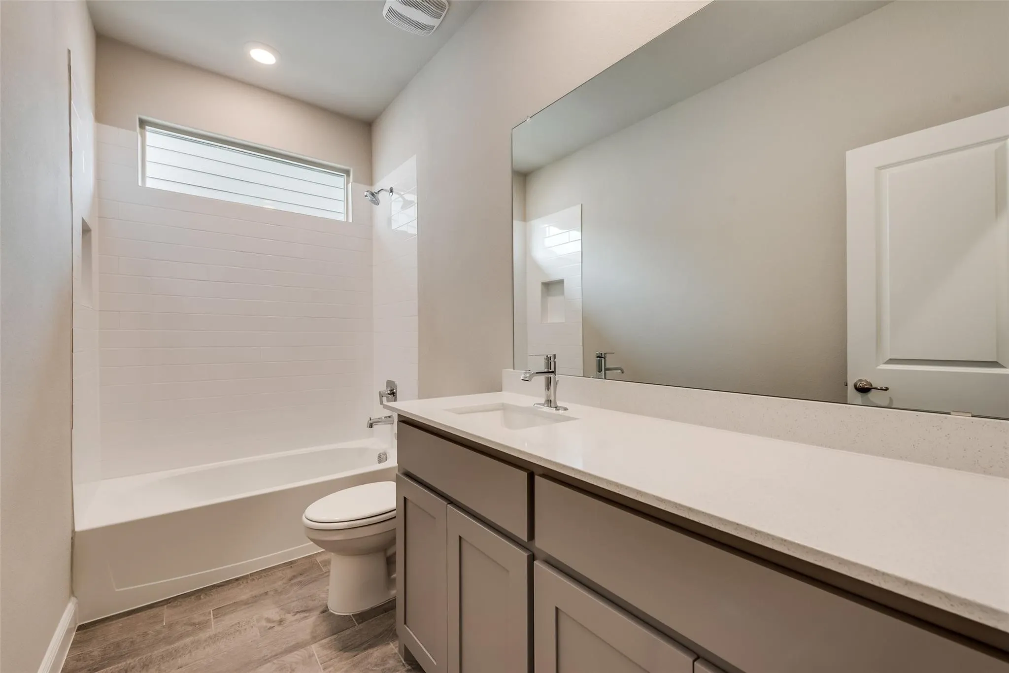 Full bathroom featuring bathing tub / shower combination, toilet, vanity, and wood-type flooring
