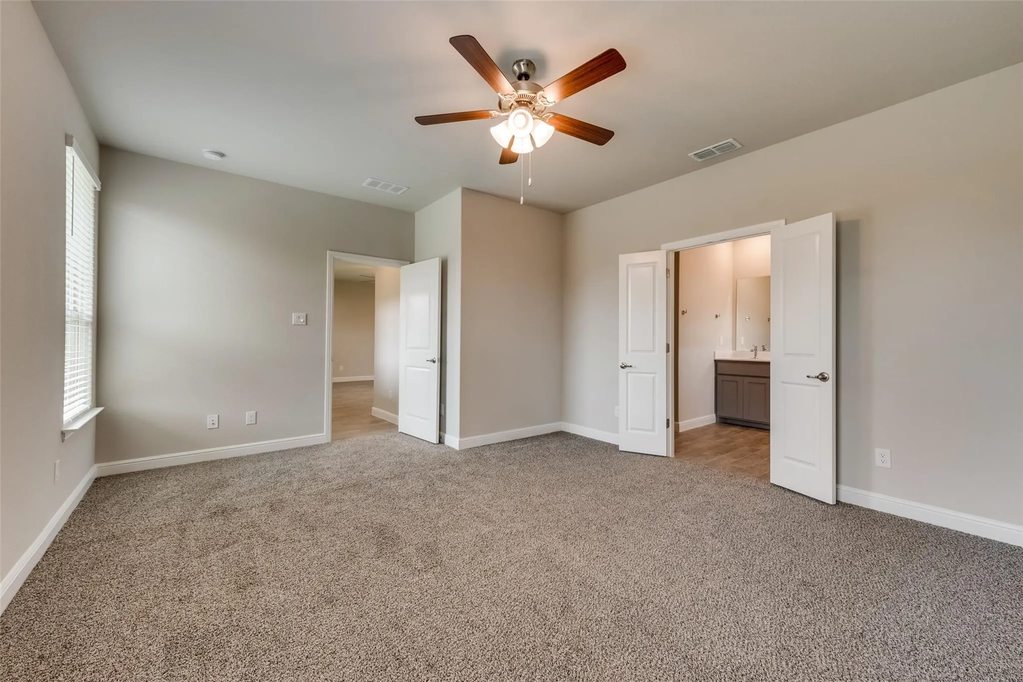 Unfurnished bedroom featuring ensuite bathroom, carpet, and ceiling fan