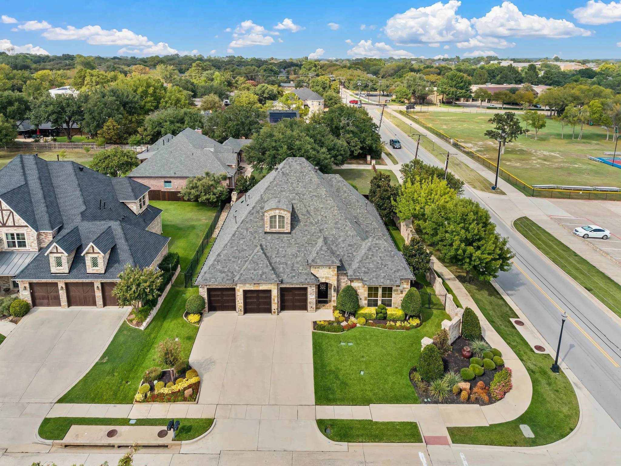 Stone and brick exterior with a multi-gabled roof, featuring a triple garage and manicured landscaping