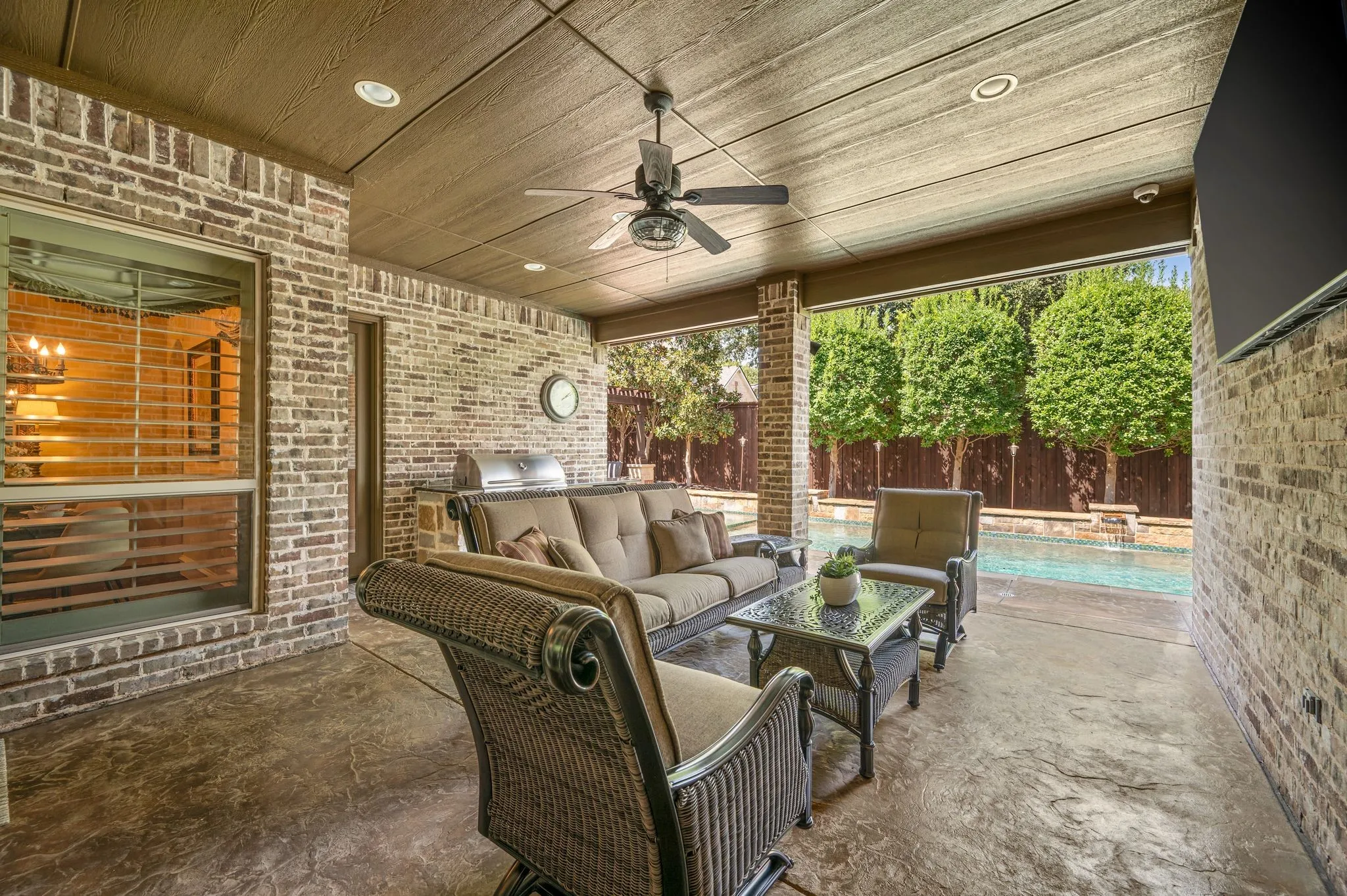 Covered patio featuring a built-in outdoor kitchen, ceiling fan, recessed lighting, and brick construction