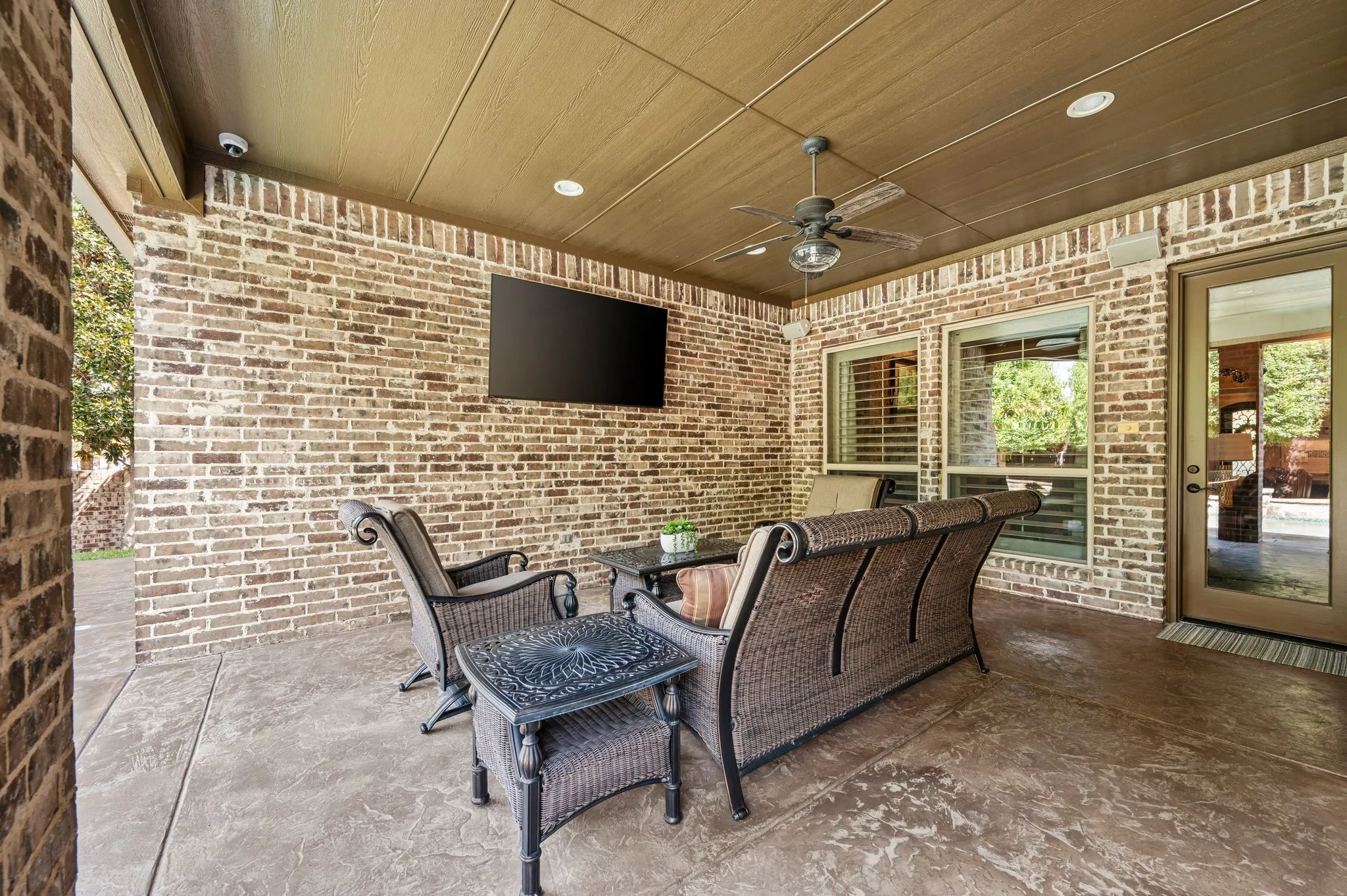 Covered patio featuring a brick exterior, ceiling fan, recessed lighting, and a mounted television