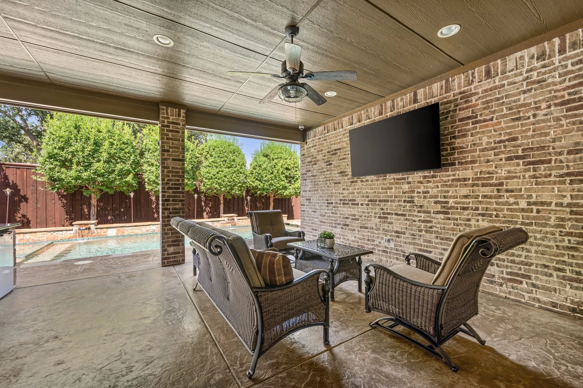 Covered patio with a brick accent wall, stamped concrete flooring, a ceiling fan, and recessed lighting