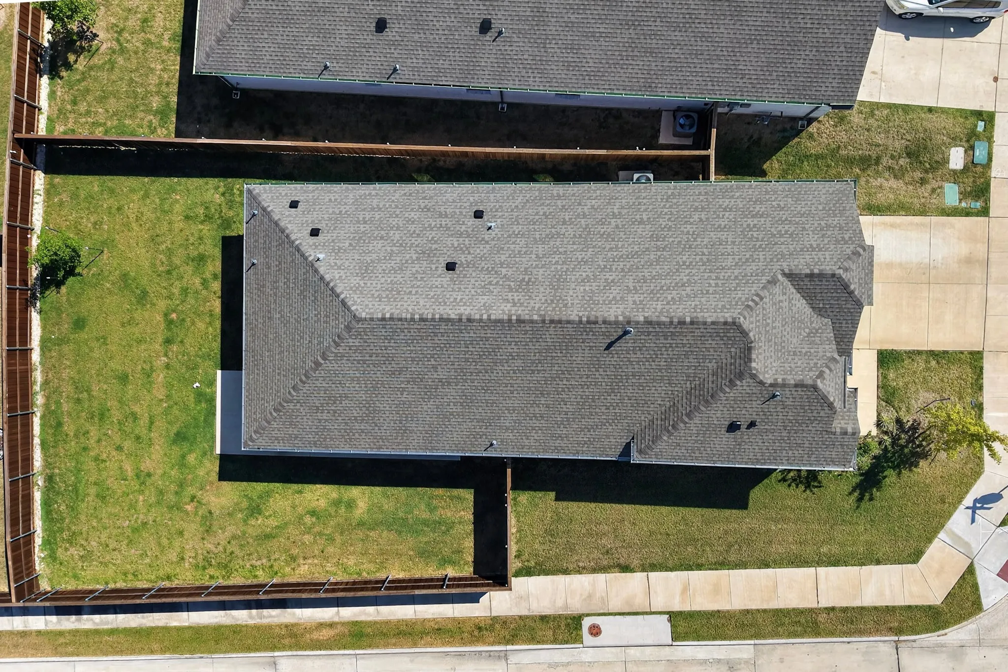 Pitched shingle roof, well-maintained lawn, and wood privacy fencing