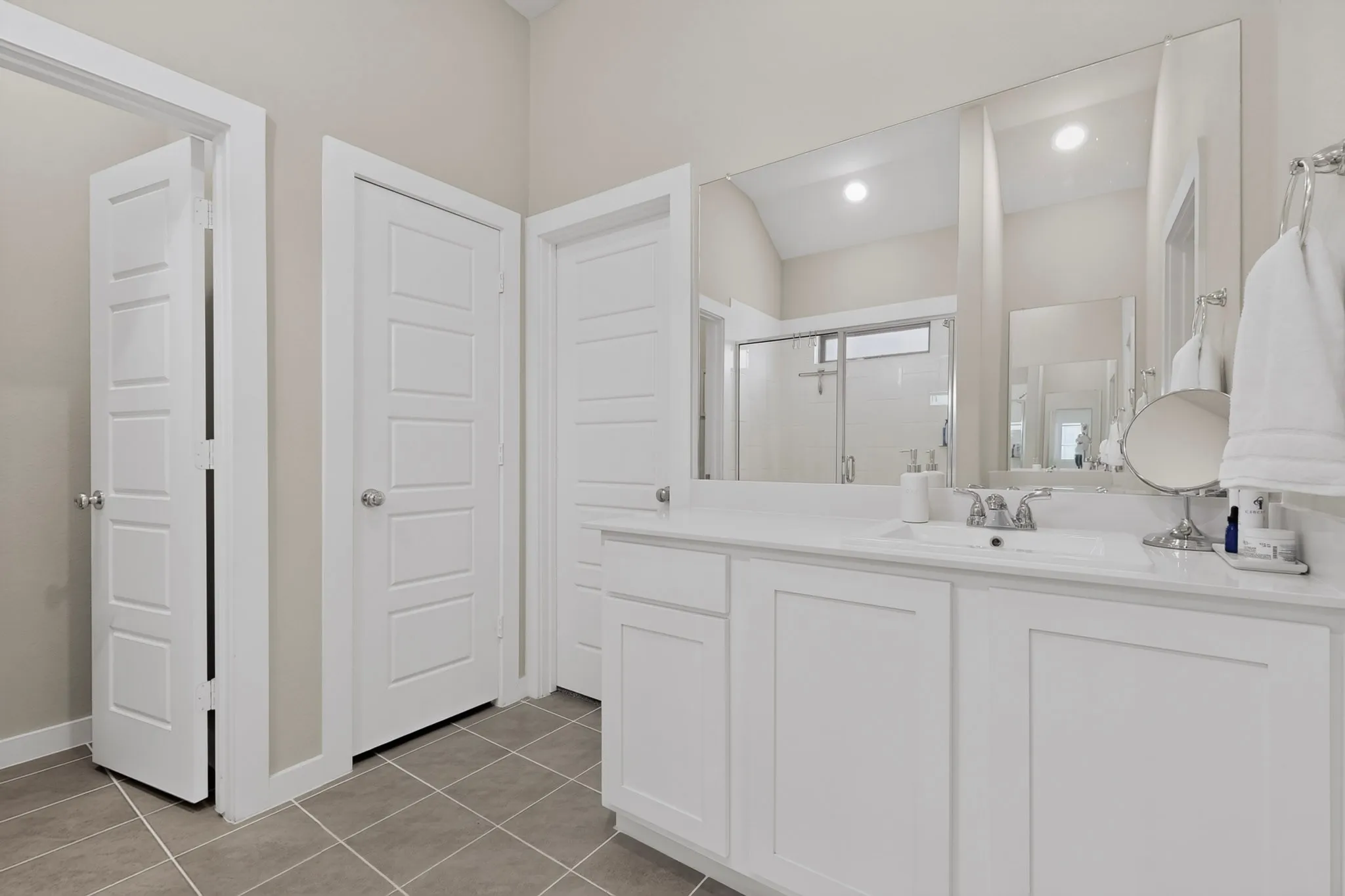 White vanity with an integrated sink, polished chrome faucet, and expansive wall-mounted mirror