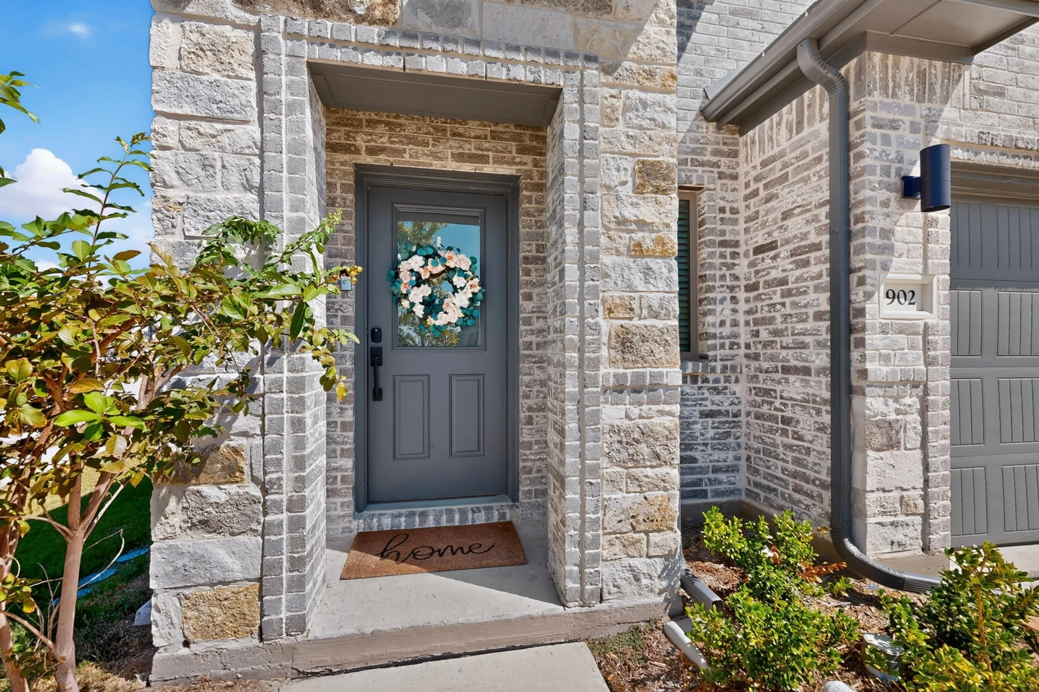Stone and brick facade with a recessed entry, dark gray front door with glass paneling, and coordinated garage door