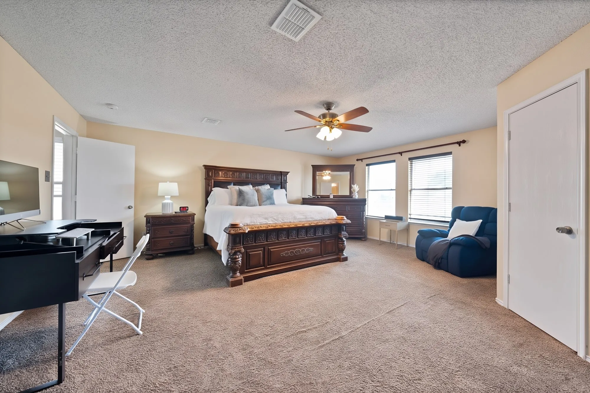 Carpeted bedroom with a ceiling fan, two windows with blinds, and neutral wall paint