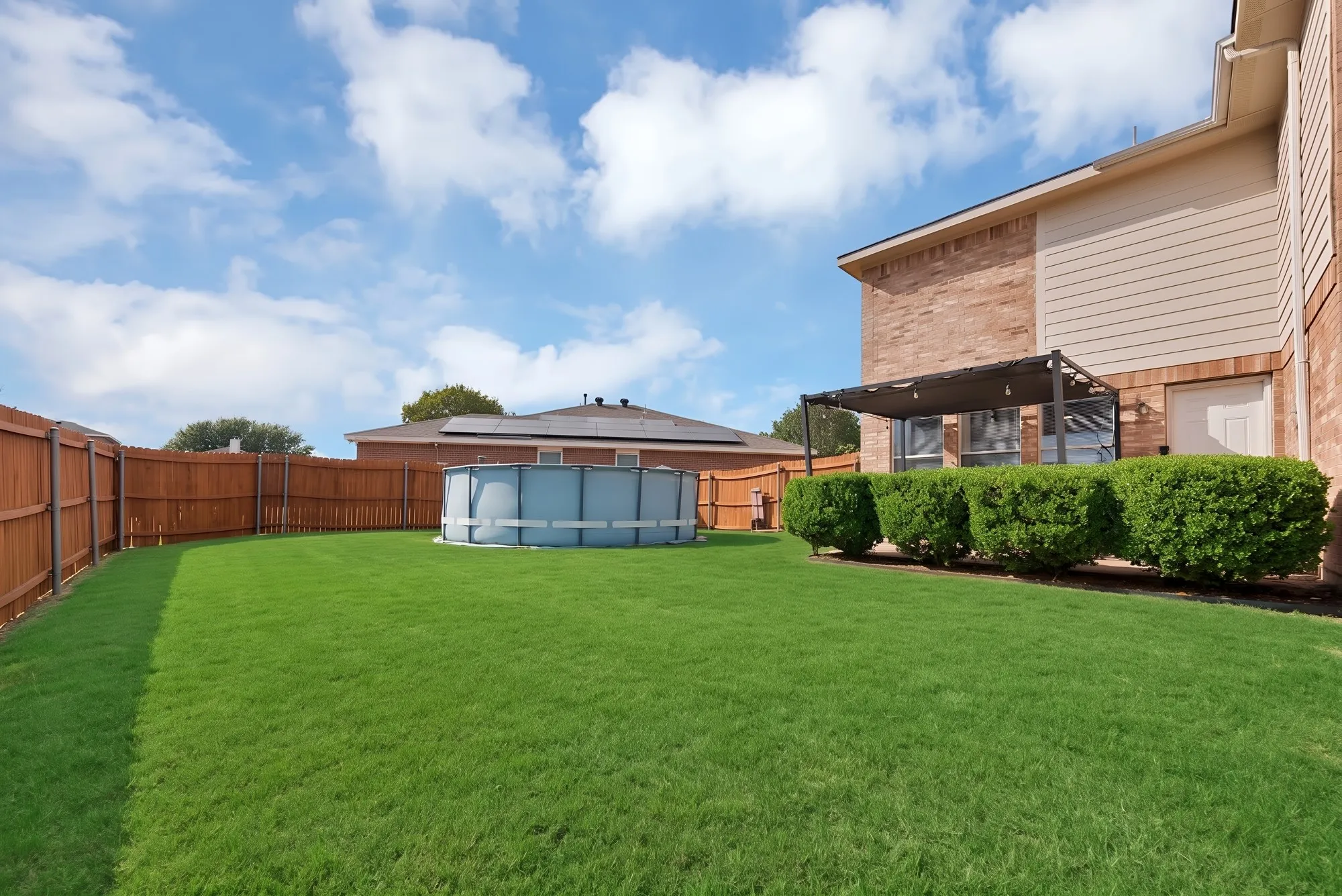 Expansive backyard with a manicured lawn, wood privacy fencing, and a brick and siding exterior
