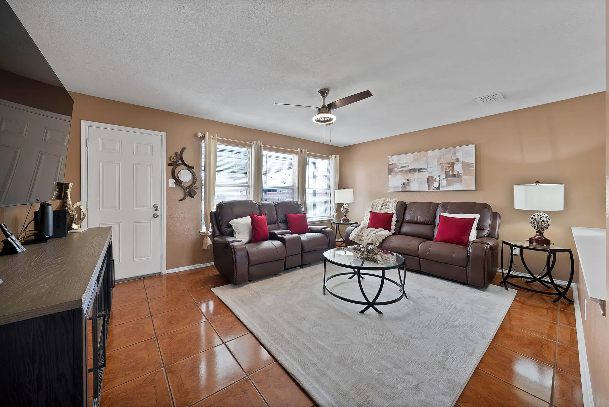 Living area featuring tile flooring, multiple windows, and a ceiling fan