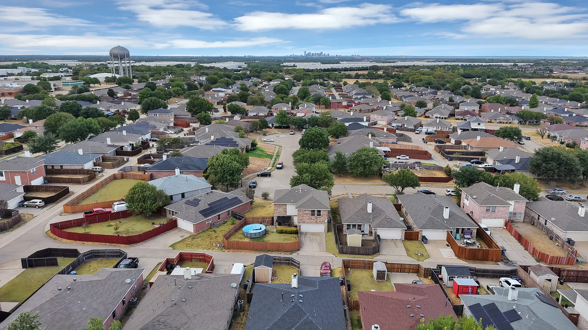 Residential neighborhood with a water tower, a distant cityscape, and a body of water in the background