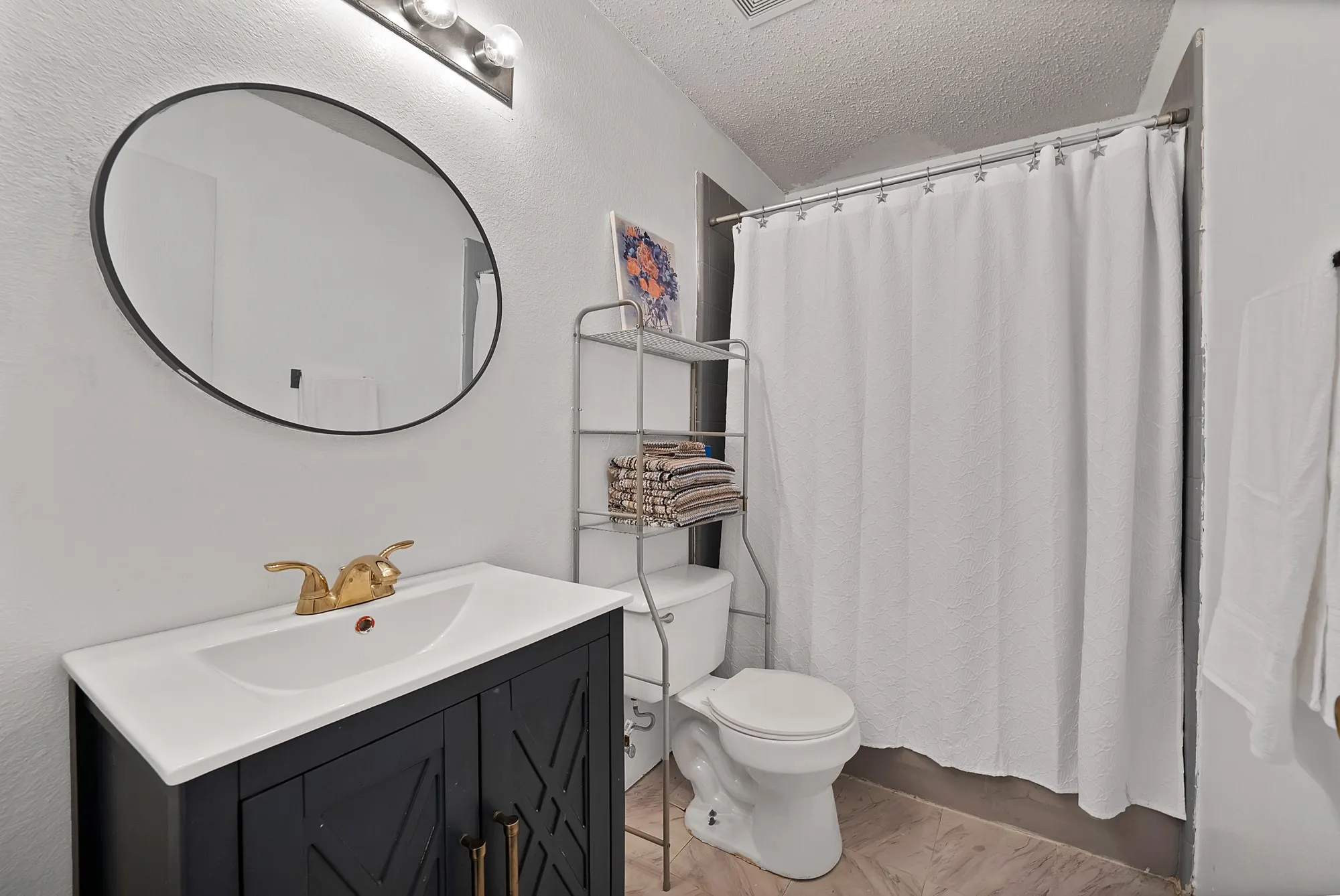 Vanity with a white integrated sink, gold-tone faucet, and dark wood-finish cabinetry