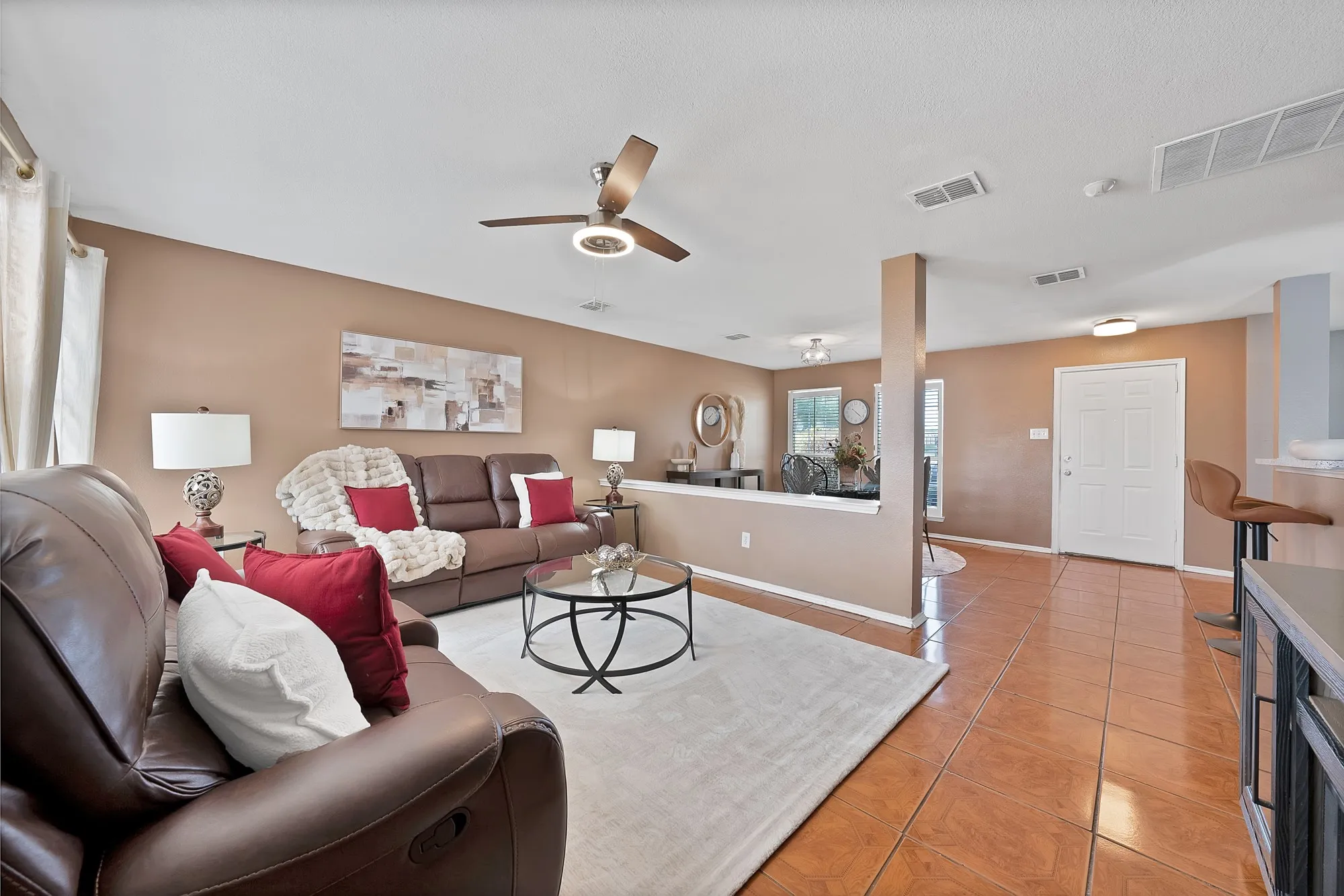Neutral wall tones, ceiling fan with integrated lighting, tiled flooring, and a white entry door